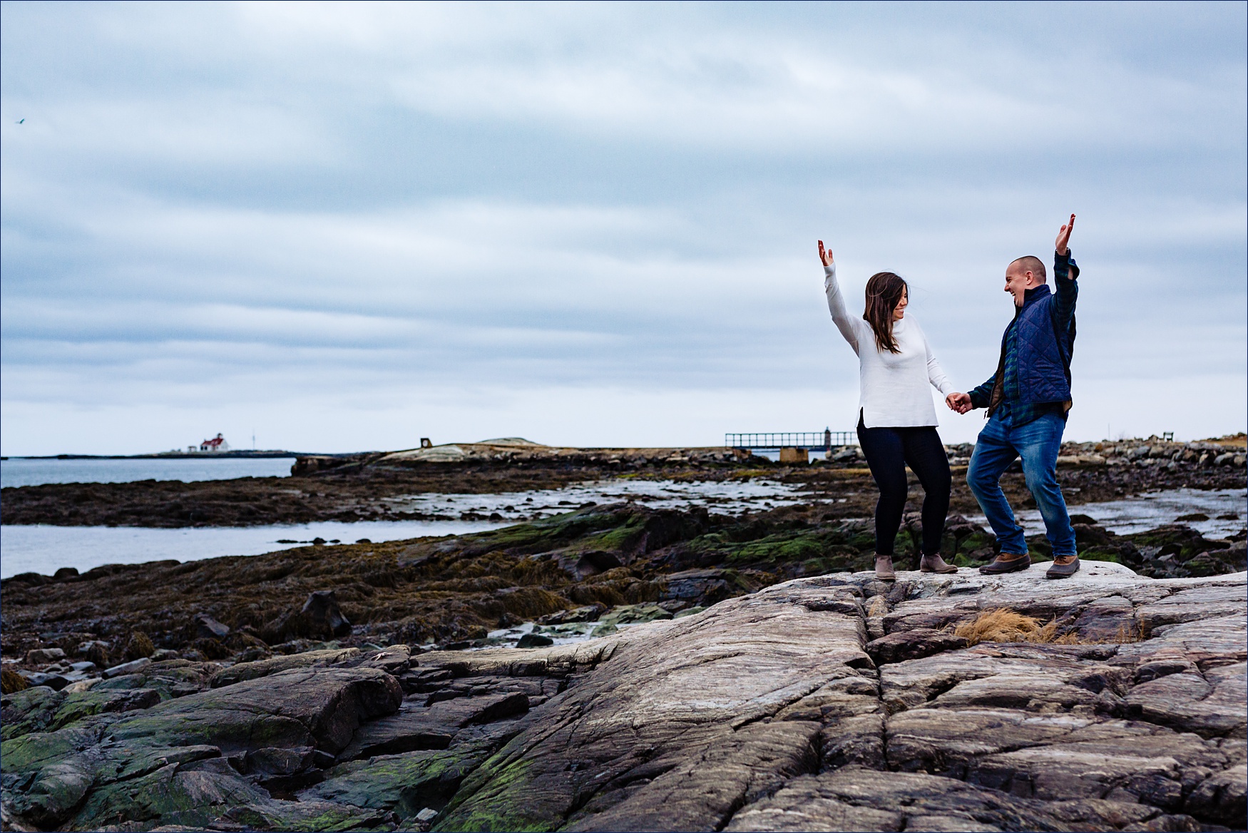 The couple dance and have fun with the dark blue sky and the rocks of Great Island Common NH all around them
