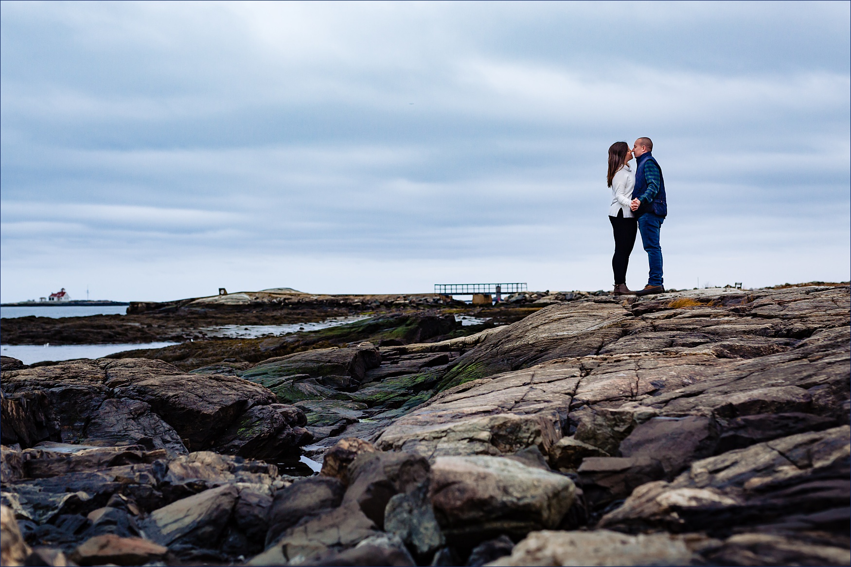 The couple kiss with the dark blue sky and the rocks of Great Island Common NH all around them