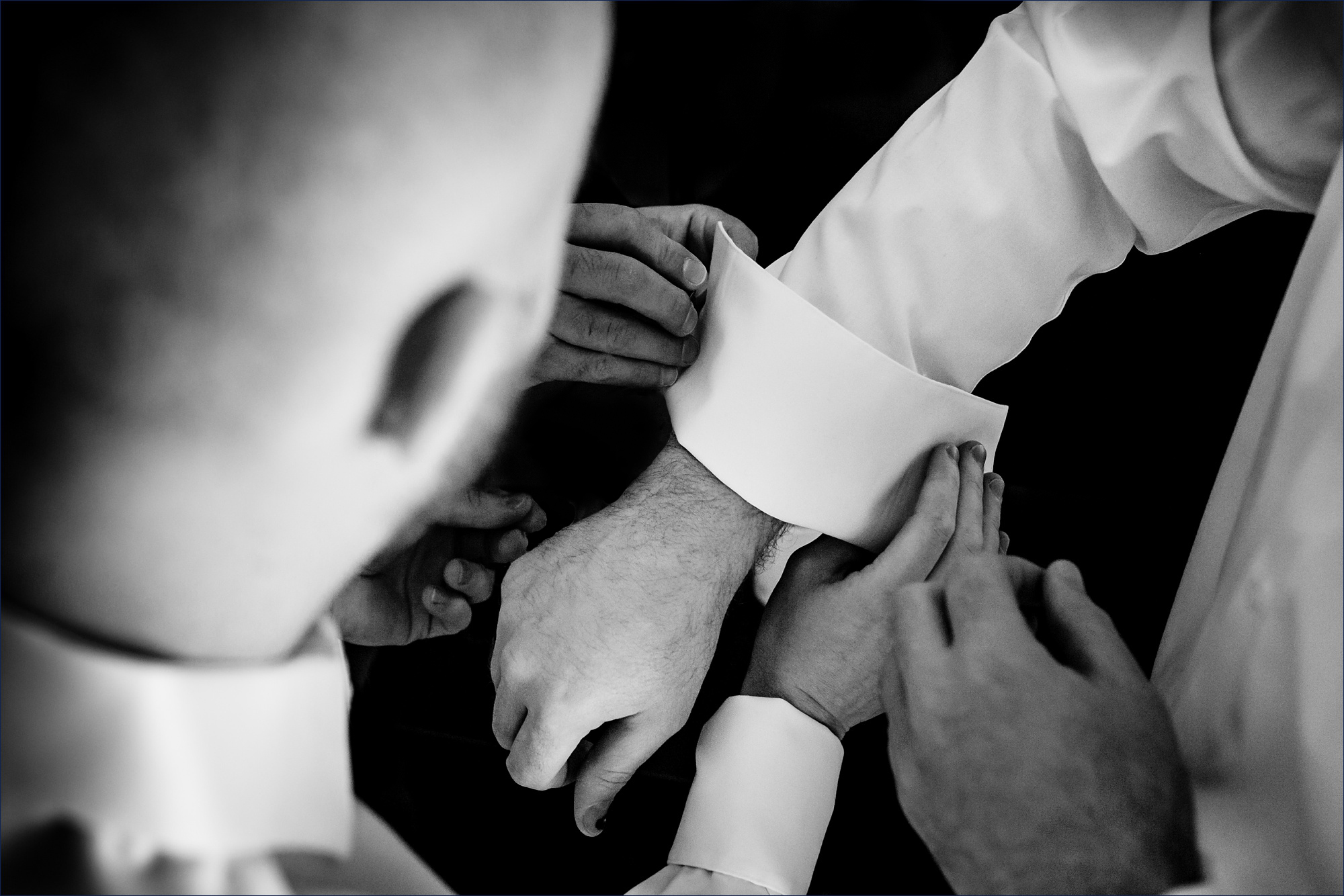 Getting the cufflinks on with groomsmen help on the winter wedding day