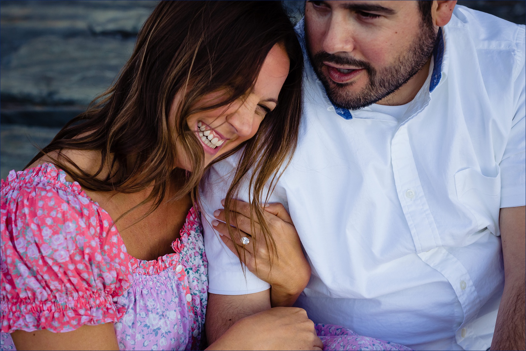 Cuddling close on the rocks of Bald Head Cliff for their engagement session