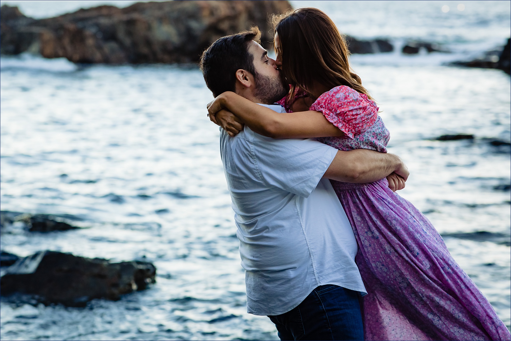 The couple kisses in front of the deep blue ocean water in Ogunquit