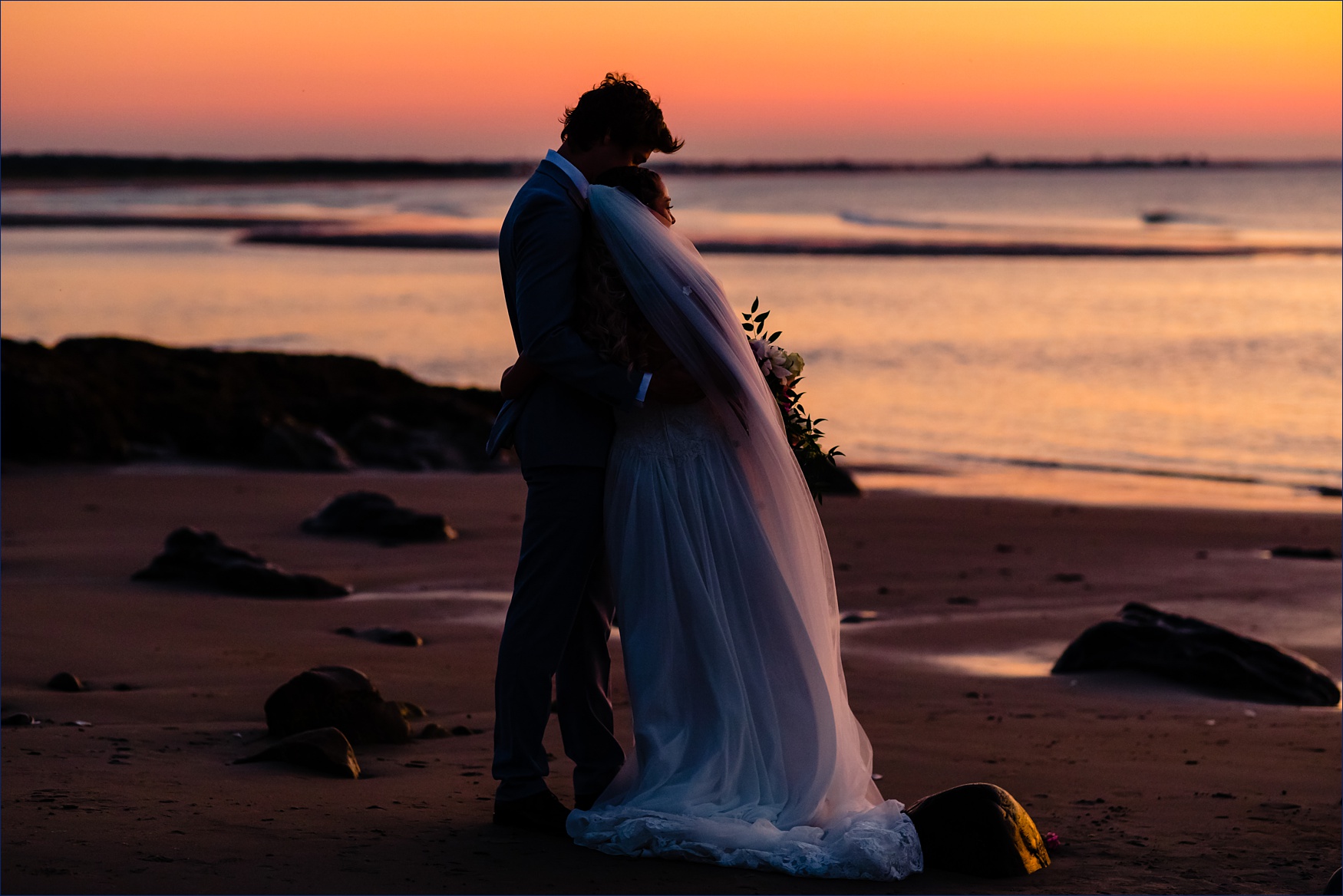The bride and groom take in the sunrise over the ocean on their Maine elopement