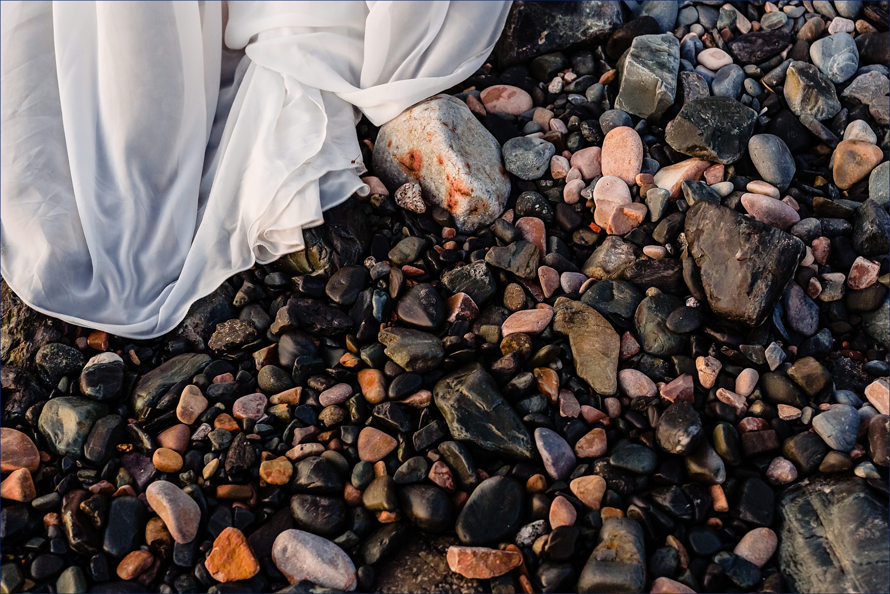 The bride's dress on the rocky shore of the beach