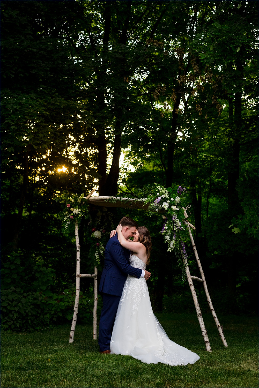 Holding one another close as the sun begins to set on the wedding day among the tall trees