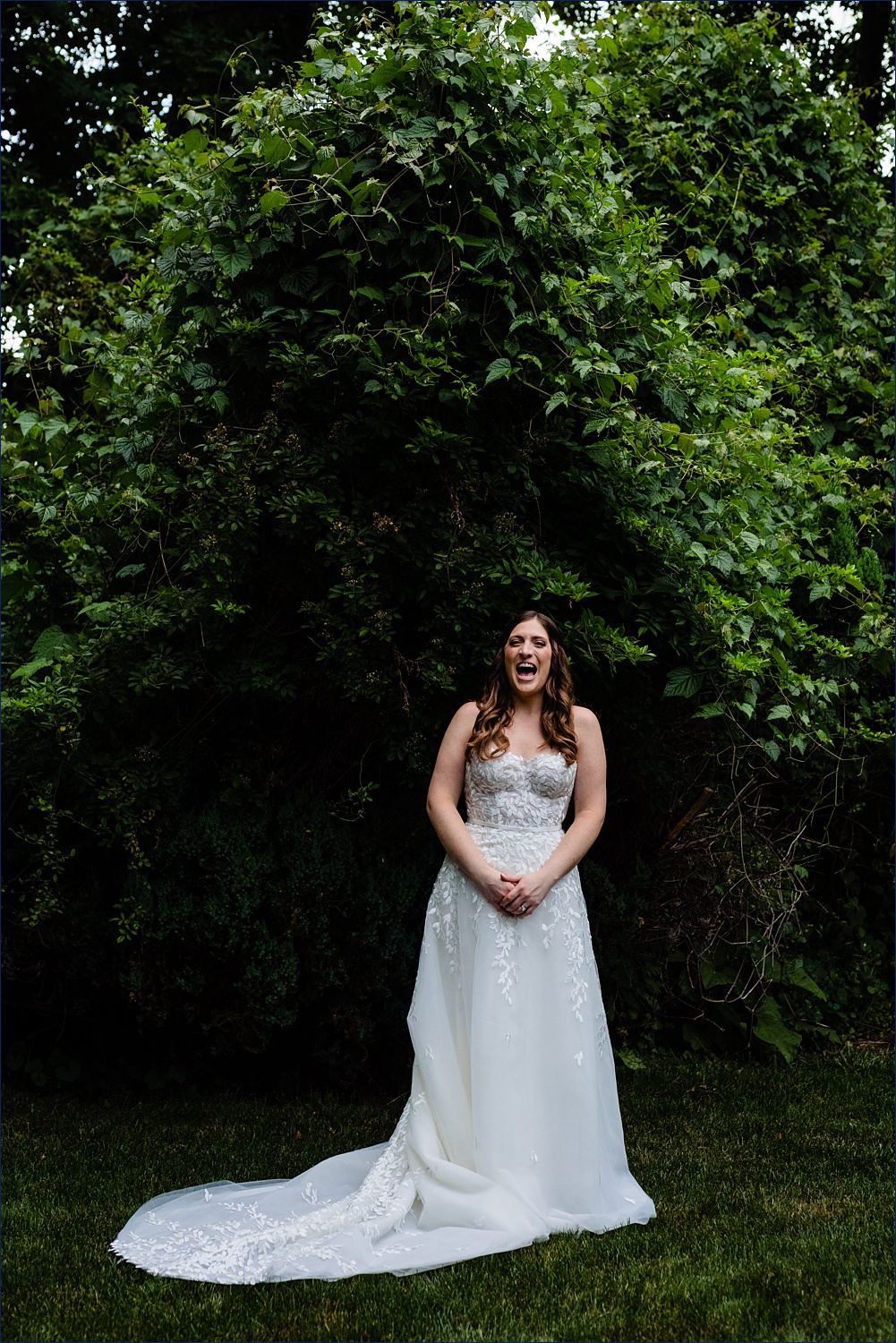A beaming bride on her wedding day among the gorgeous greenery in the family backyard