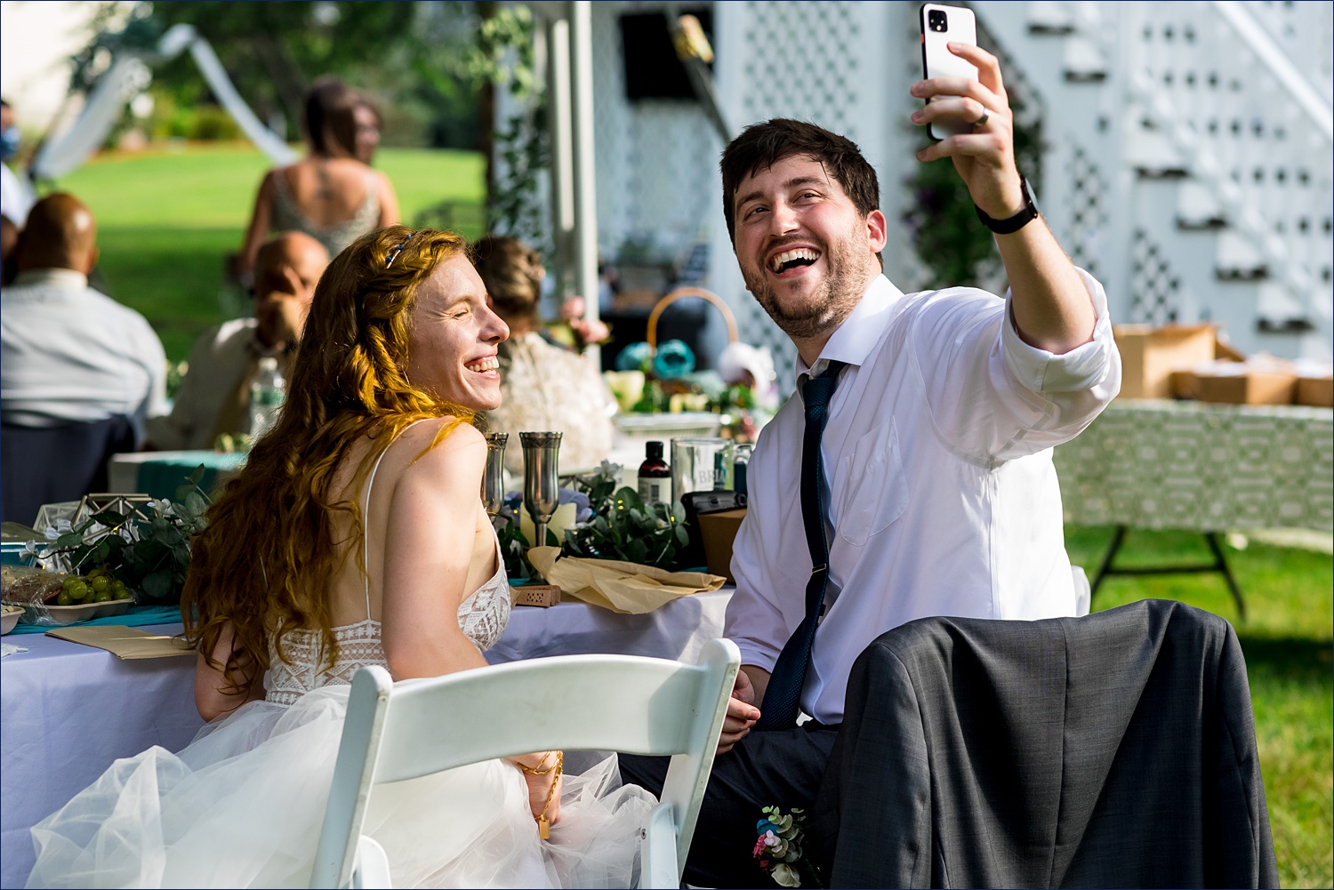 The bride and groom laugh on a Facetime call during their intimate backyard wedding in Andover MA