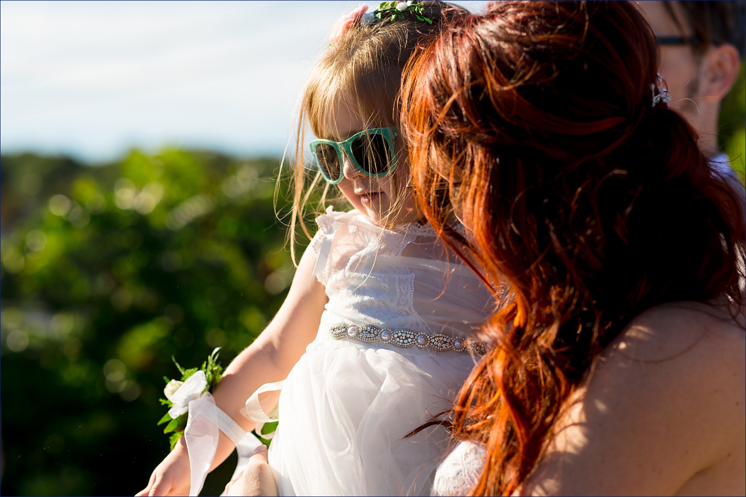 The flower girl snuggles with the bride after the wedding ceremony