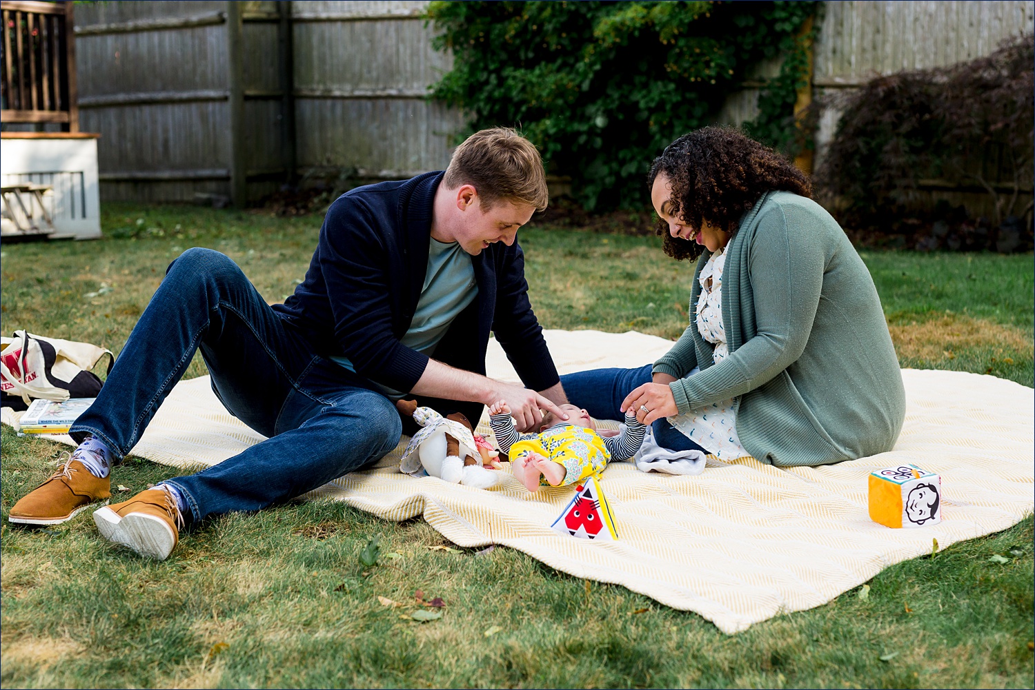The family plays on a blanket in the backyard