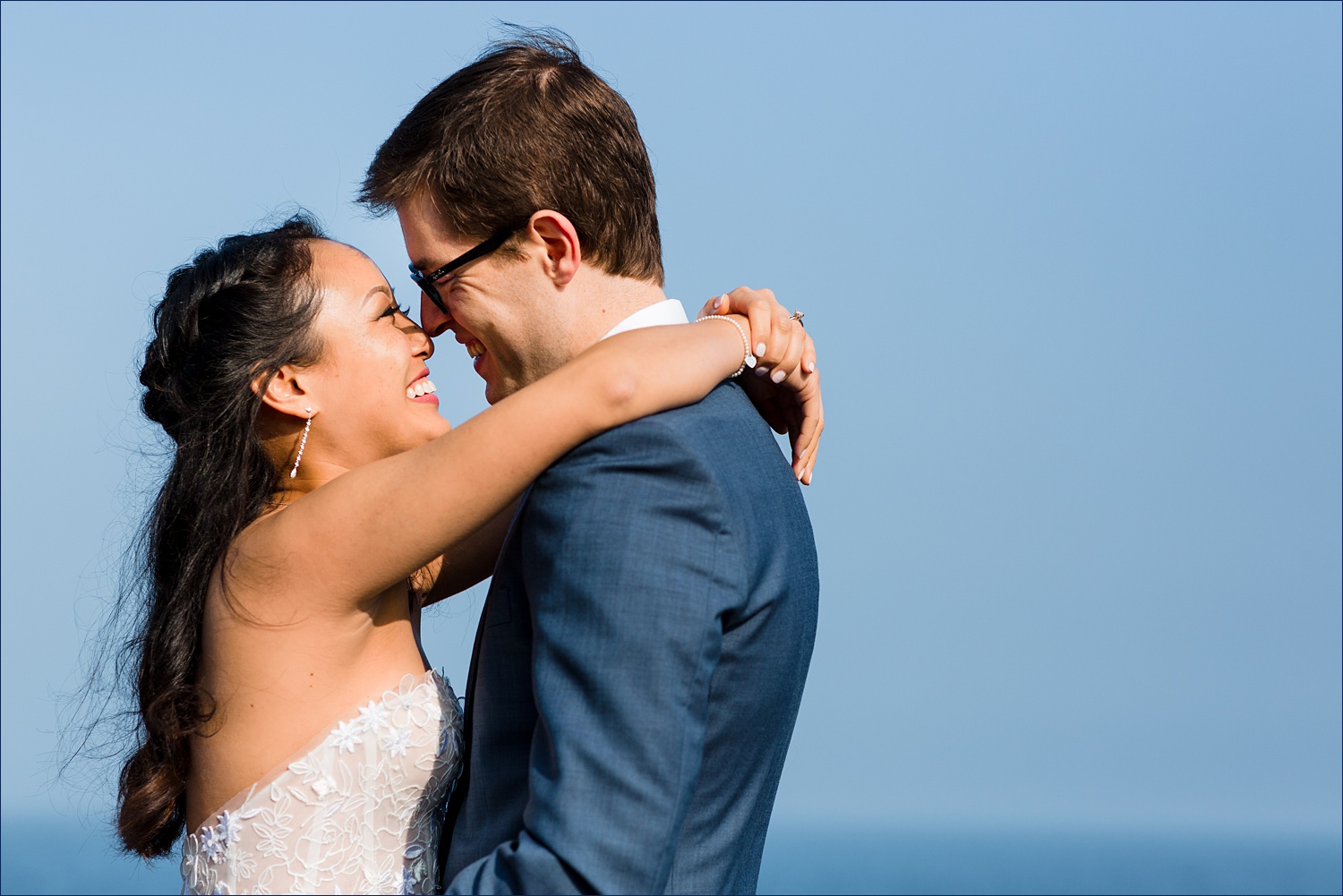 Nose to nose with a blue sky and ocean behind them on their Southern Maine elopement
