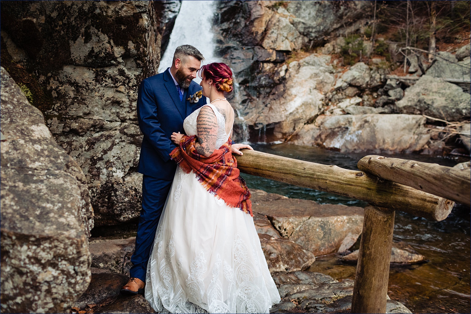 The bride and groom at Glen Ellis Falls out on the rocky waters overlooking the waterfalls before eloping