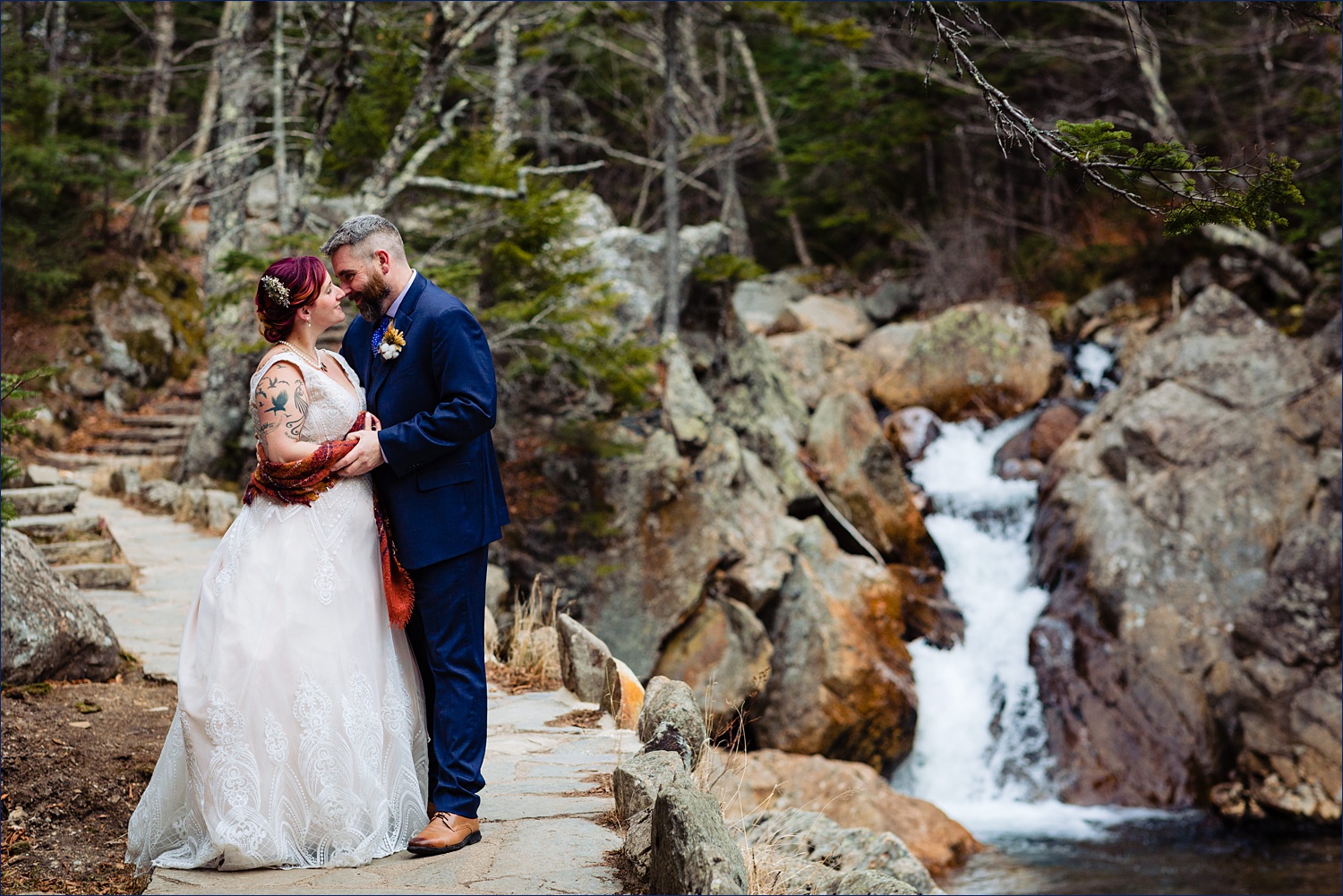 The couple and a rushing waterfall on their White Mountain Elopement