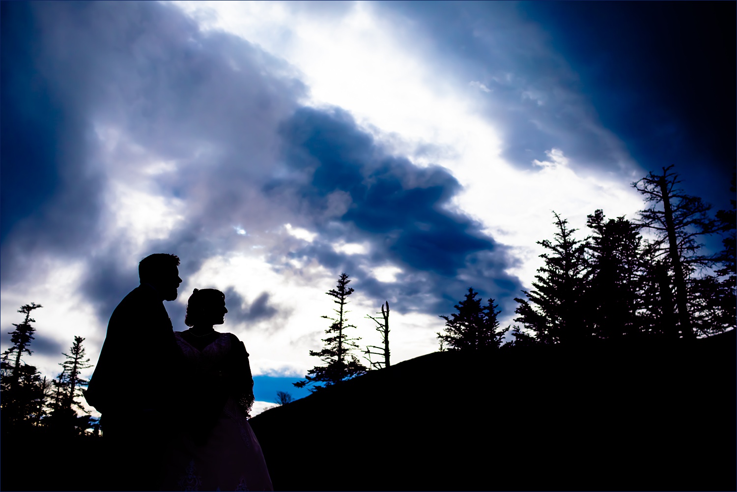 The bride and groom silhouetted against the White Mountains on the New Hampshire Elopement