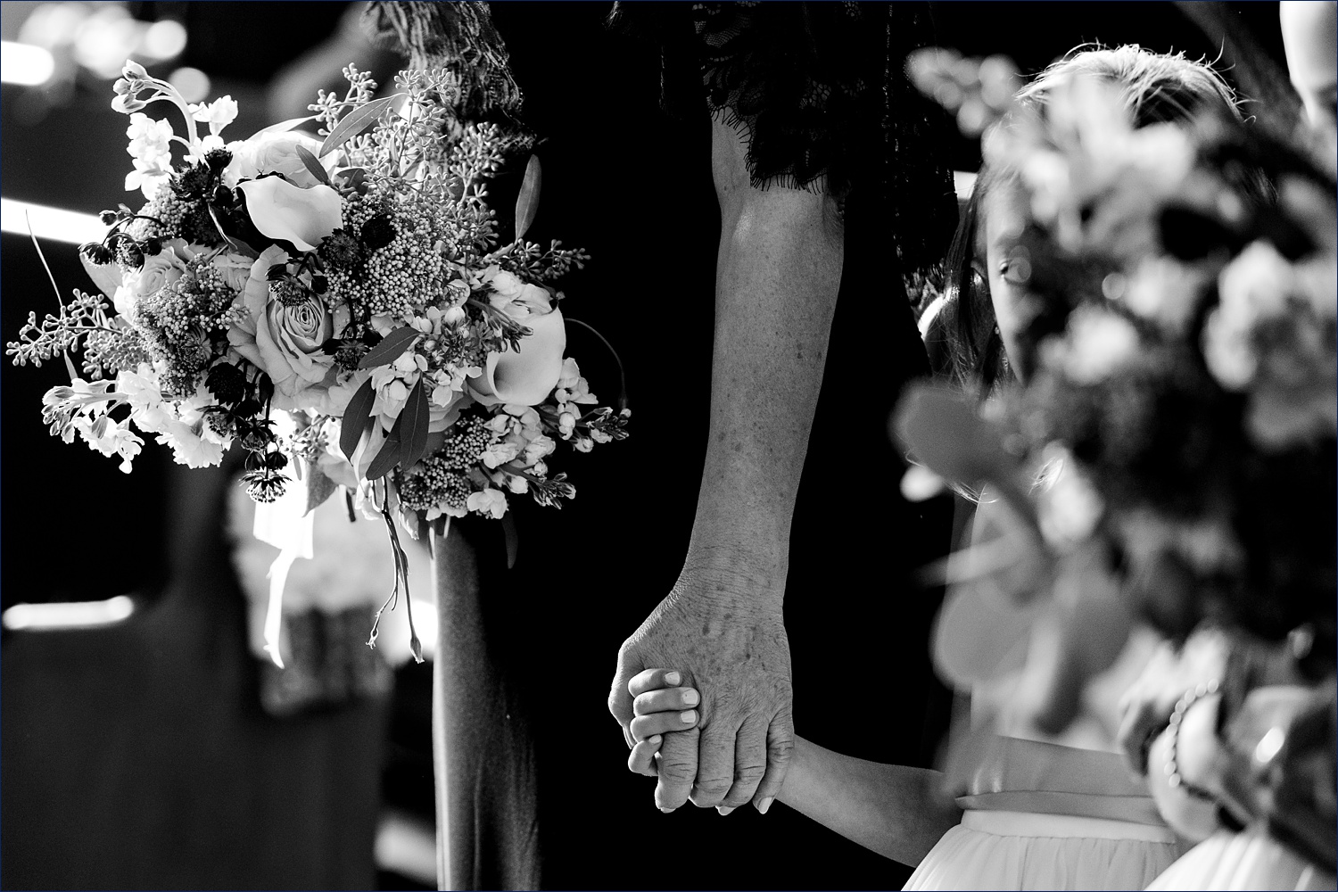 Grandma holding hands with her granddaughter during the wedding ceremony
