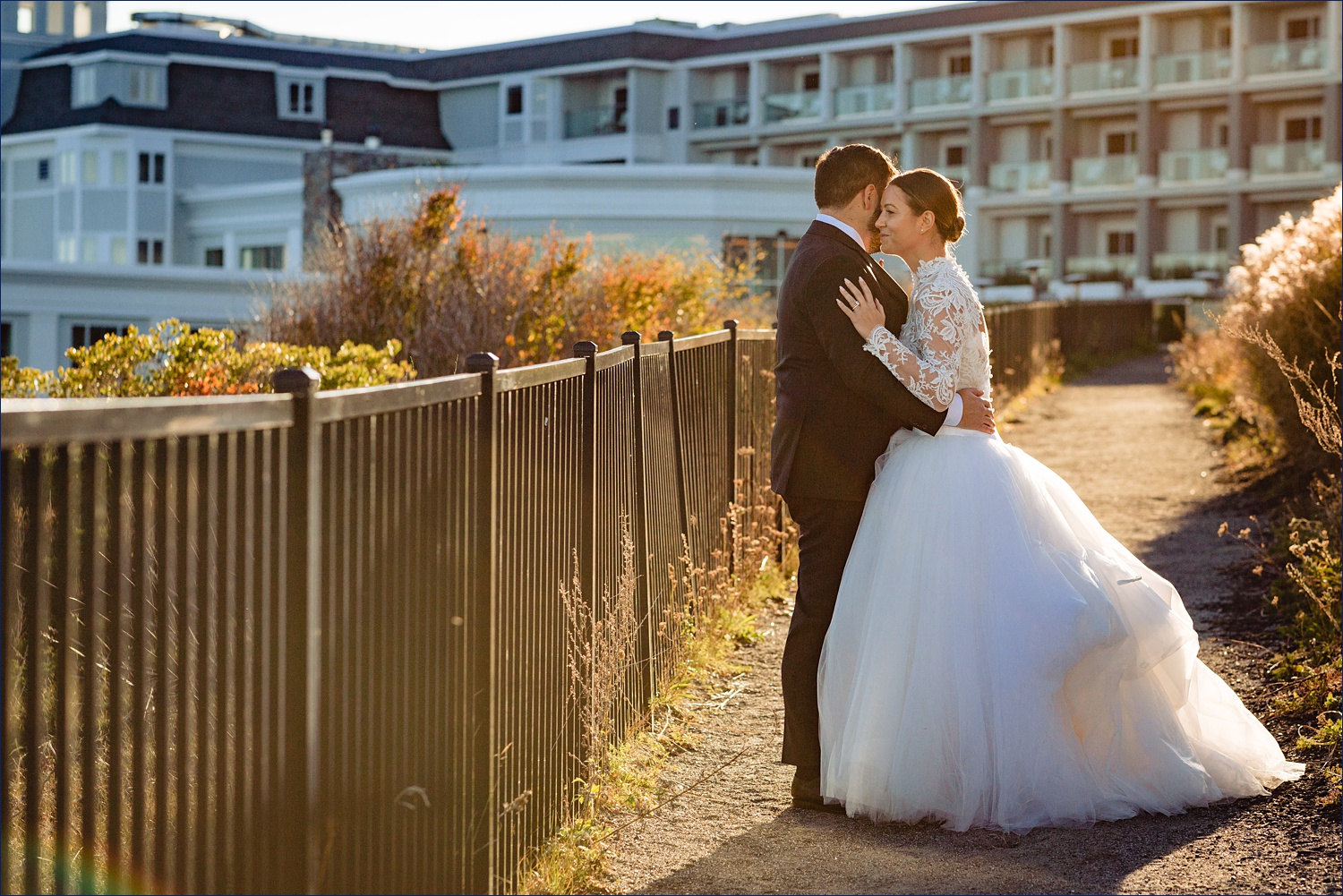 The sun sets at Cliff House over the Cape Neddick Maine building with the couple drenched in sun