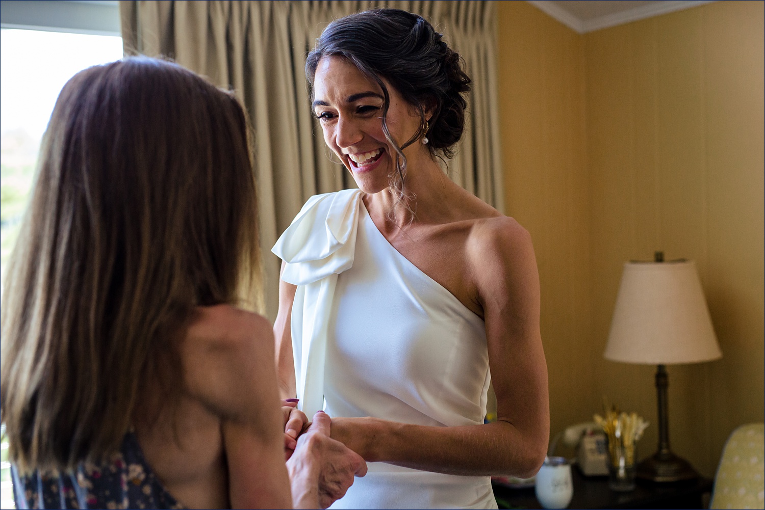 The bride greets her mom after putting on her wedding dress