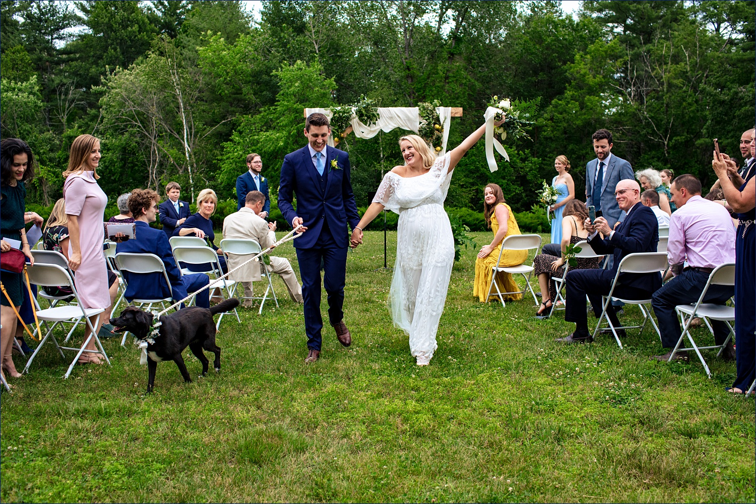 Walking back up the aisle with their dog in hand after marrying in New Hampshire