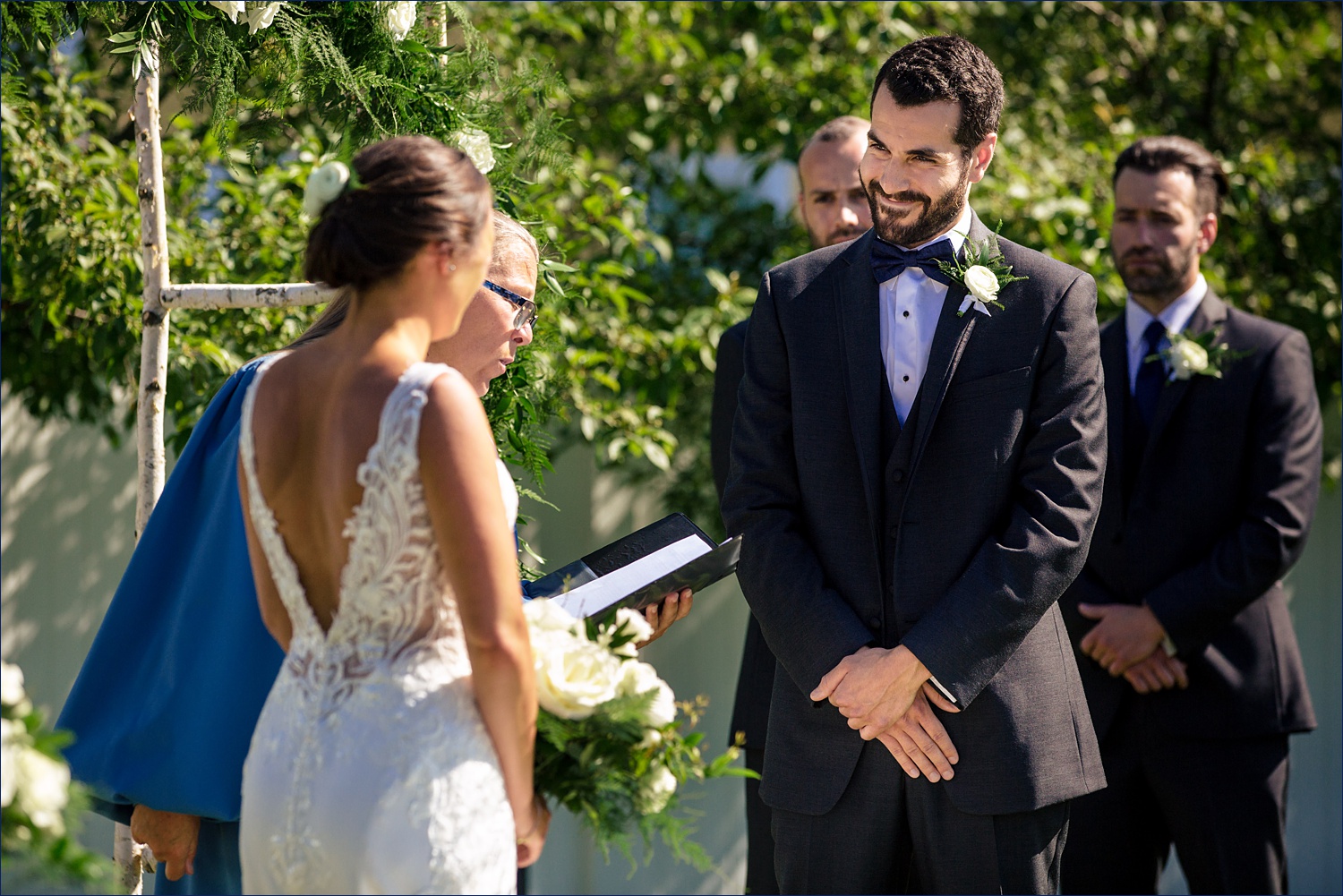 The groom steals a smile at the bride at their garden wedding in NH