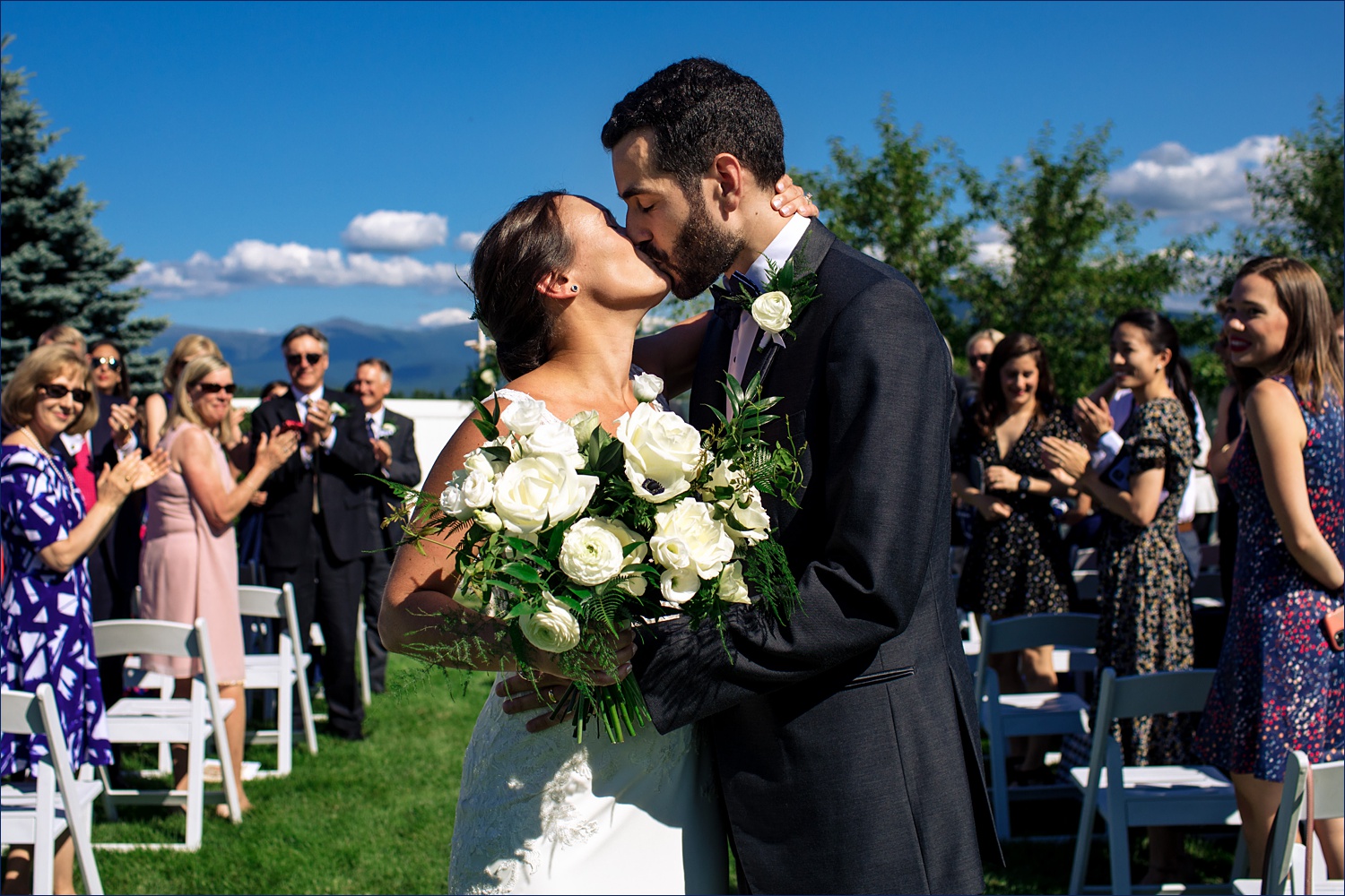 The bride and groom steal a kiss at the end of the aisle of their NH wedding day