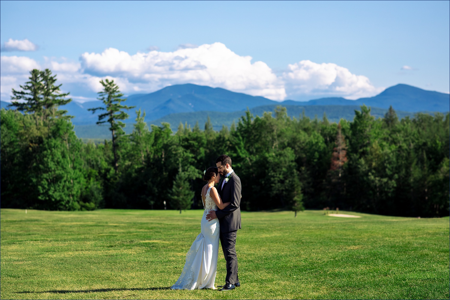 The couple hold one another close as they stand in front of the White Mountains of New Hampshire