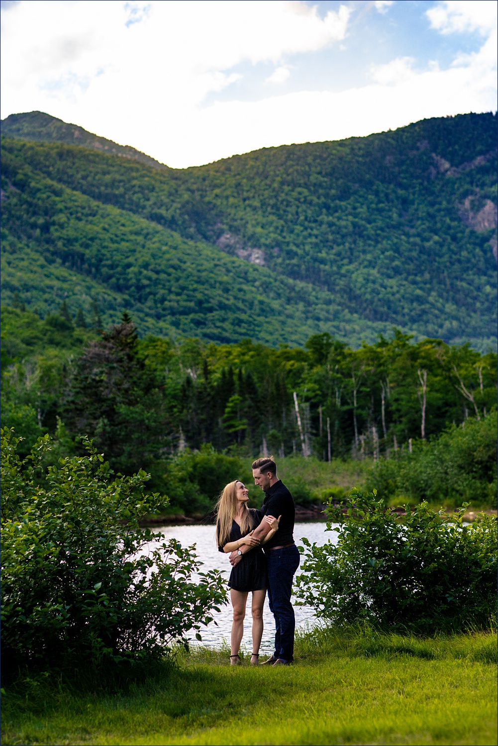 WIth the White Mountains of NH behind them, the couple embraces at their engagement session