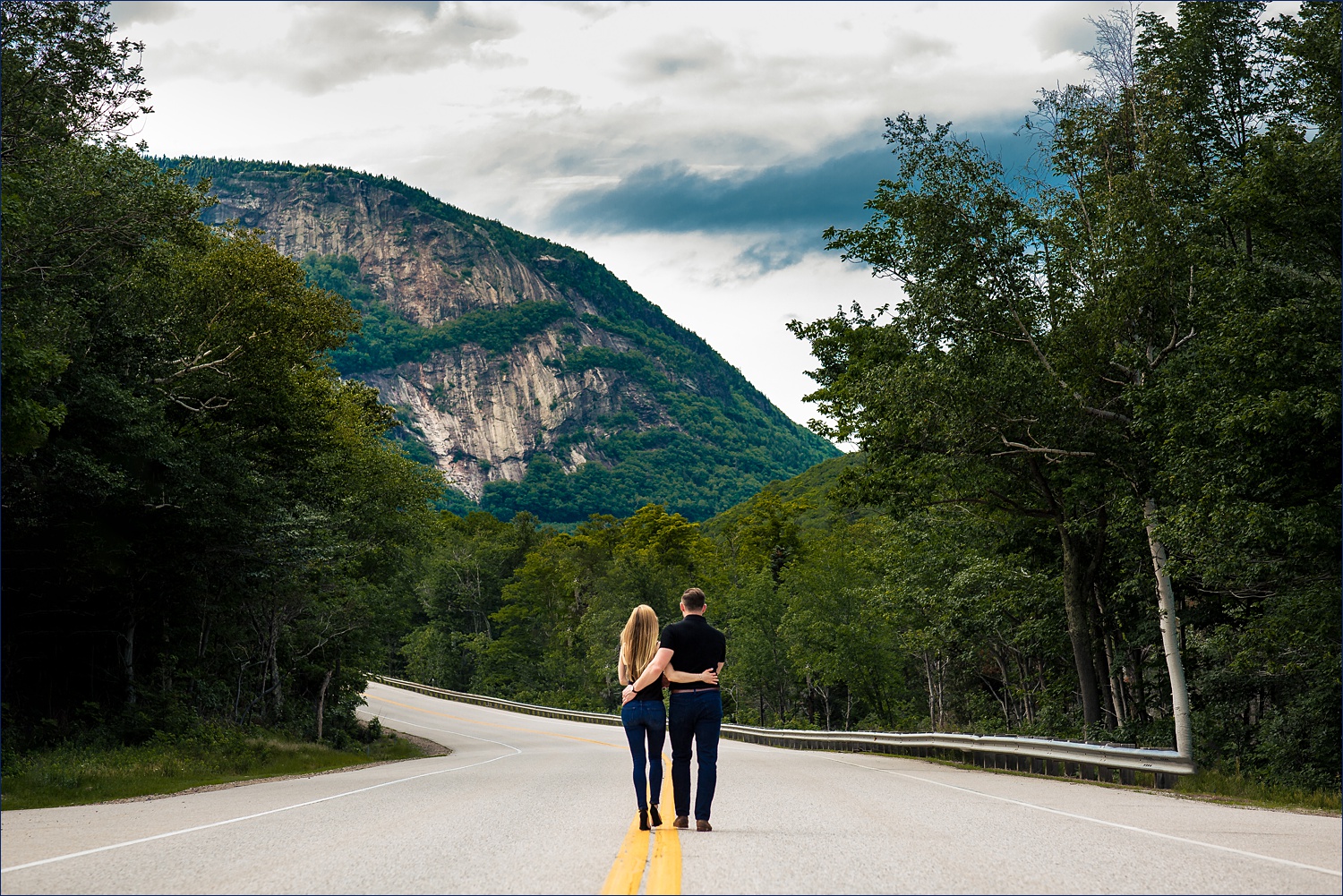 The couple walks in front of the White Mountains of New Hampshire up in Crawford Notch