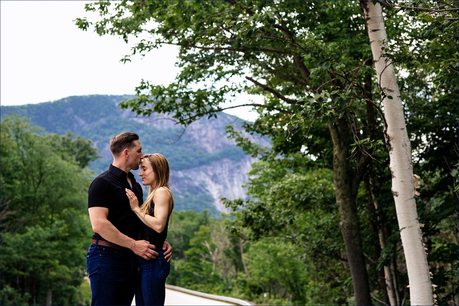 Kissing on the forehead with the White Mountains of NH behind the couple