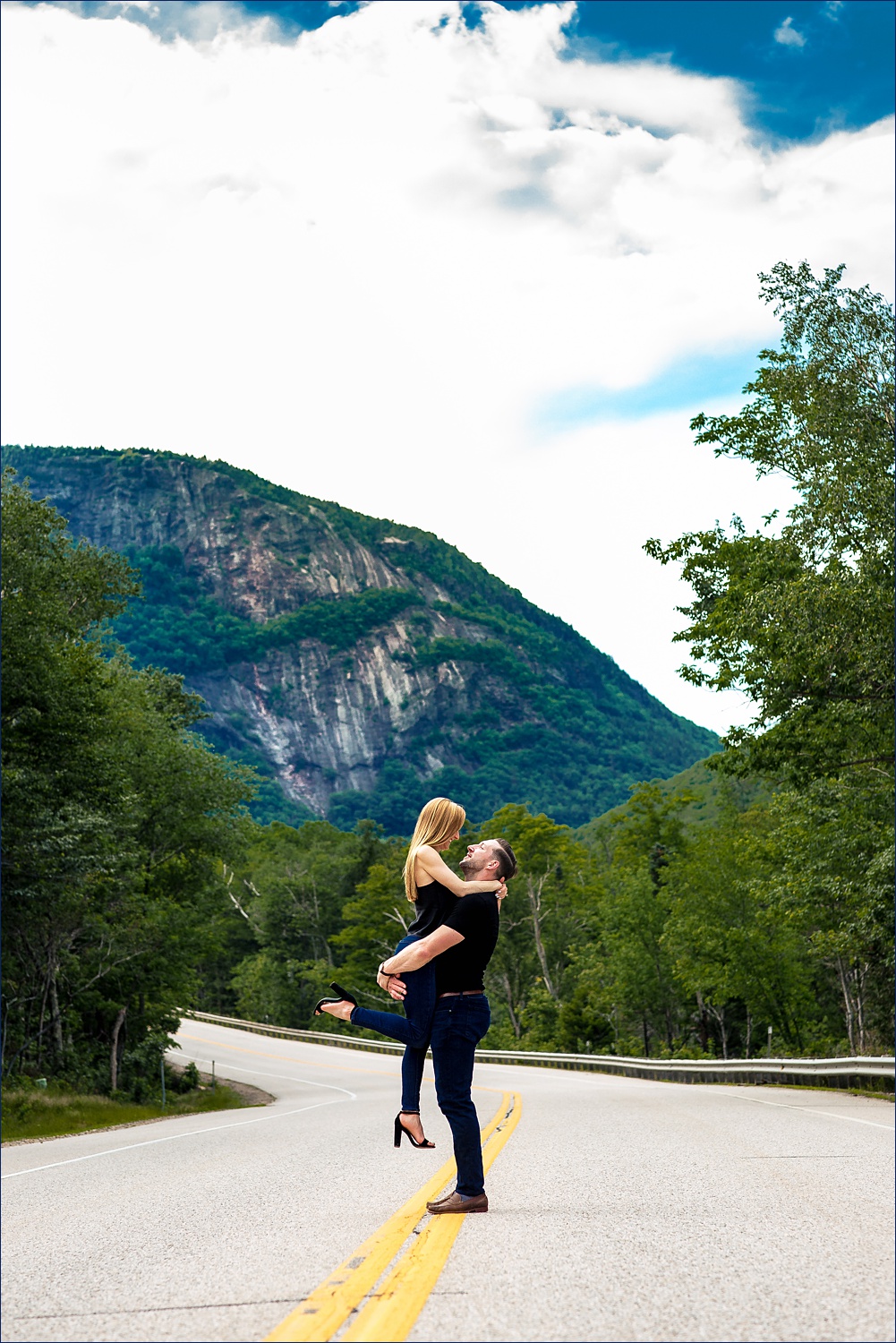 The couple embrace in front of the White Mountains of New Hampshire up in Crawford Notch
