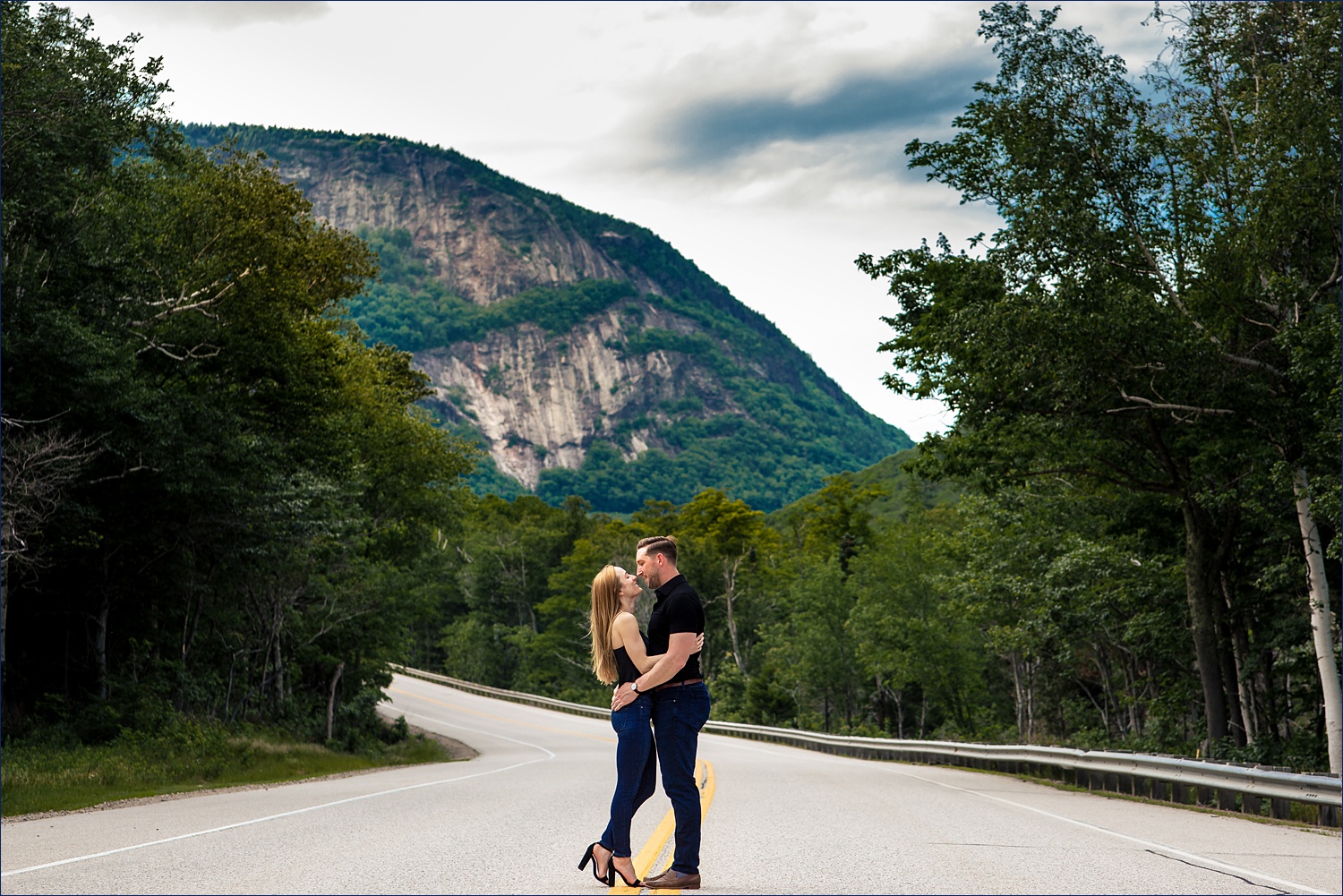 The couple kiss in front of the White Mountains of New Hampshire up in Crawford Notch