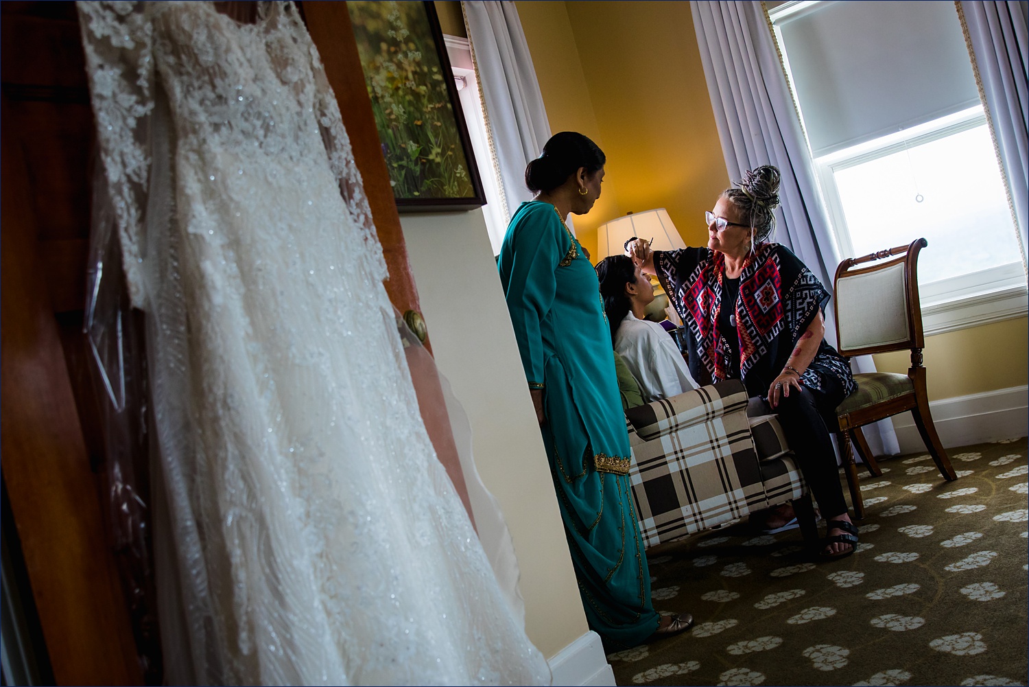 The mother of the bride watches as her daughter gets her makeup completed on her wedding day