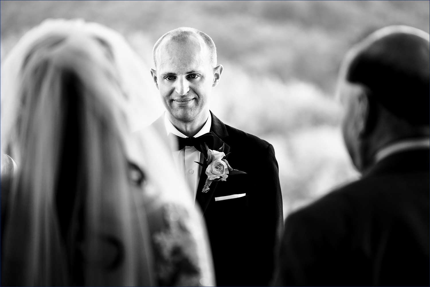 The groom watches the bride come down the aisle with loving eyes