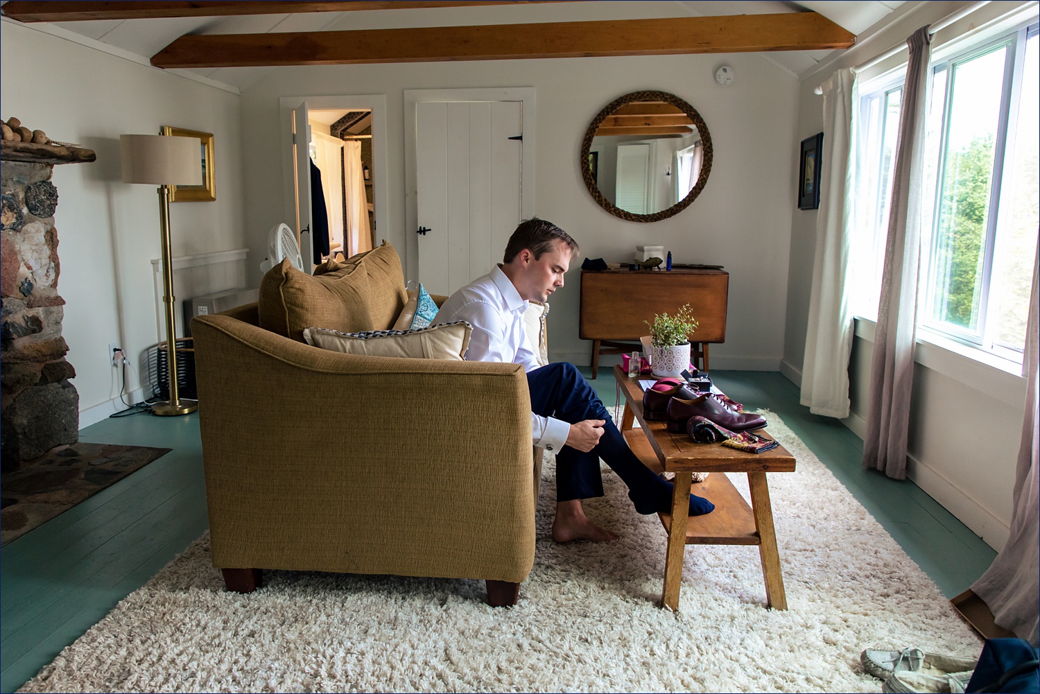 The groom gets his shoes on in his cabin in Maine