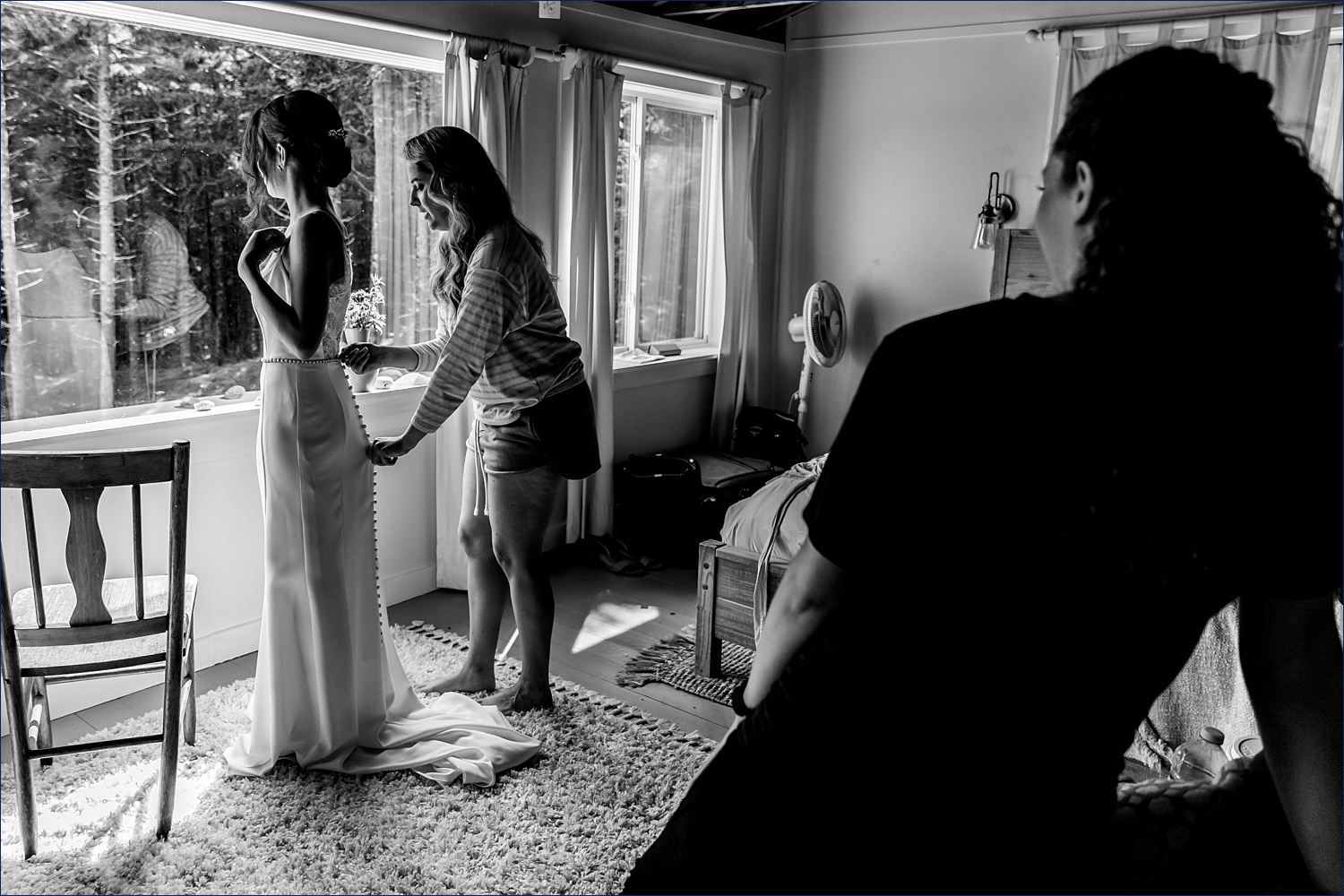 The bride gets help into her wedding gown while her friends watch at Aragosta on Deer Isle Maine