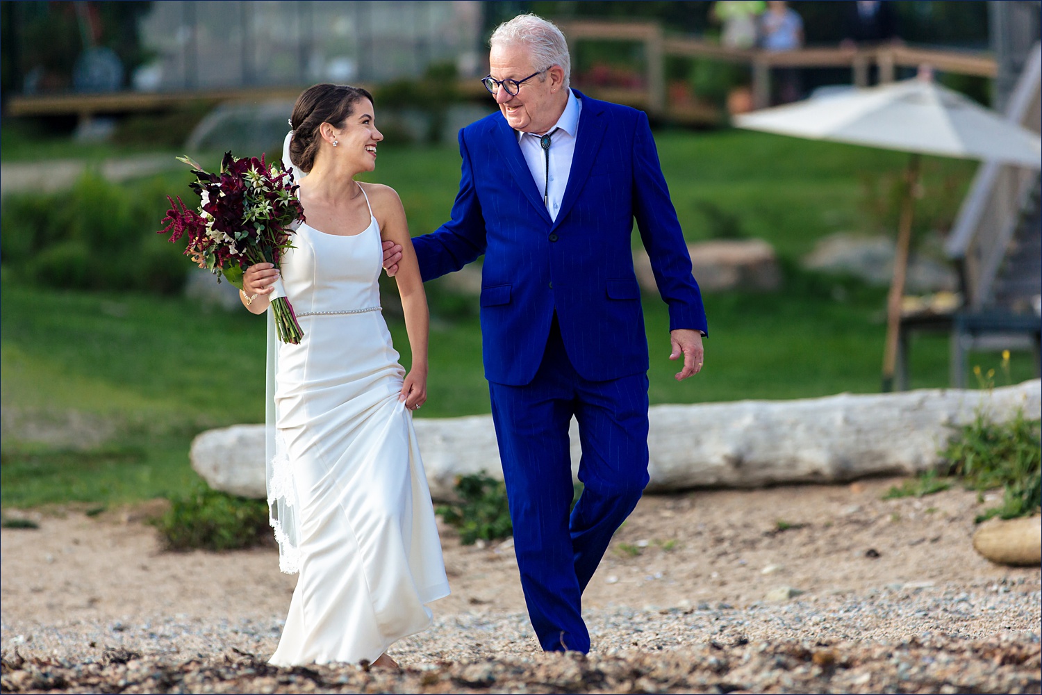 The bride and her father walk down the aisle together barefoot for the beach wedding at Aragosta