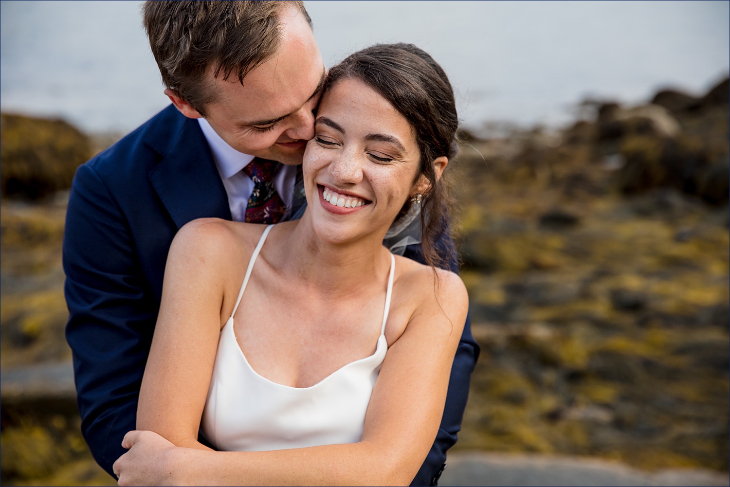 The couple laughs and hold each other close on their Deer Isle Maine wedding day