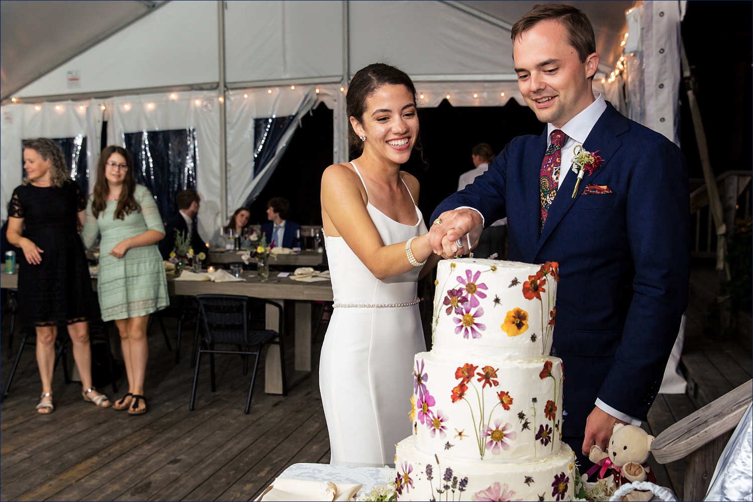 The newlyweds attempt to cut the cake on their coastal Maine wedding day
