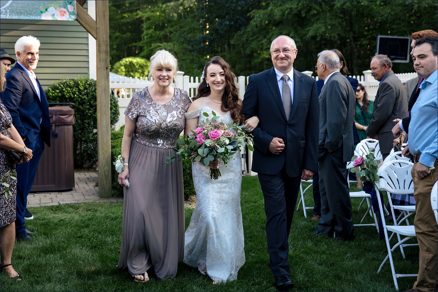 The bride comes down the aisle with her parents