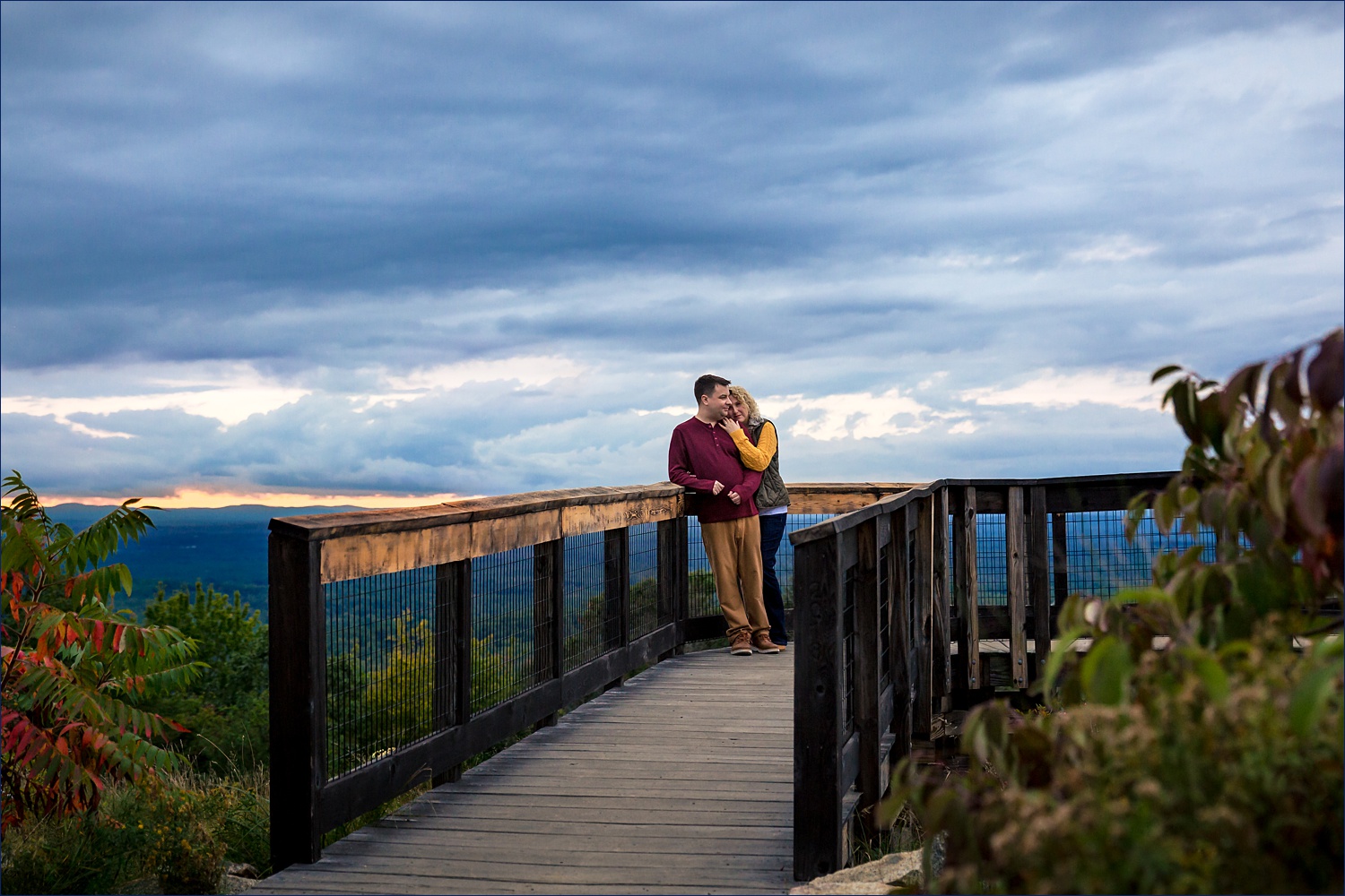 The couple holds onto each other at Mount Agamenticus in York Maine for their engagement session