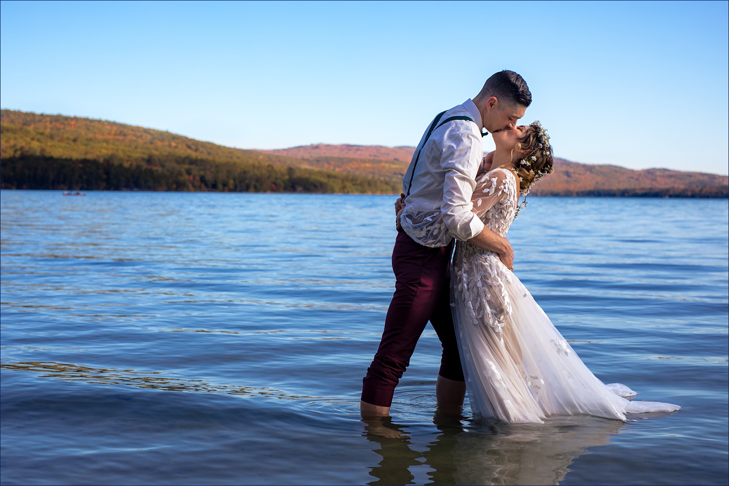 The groom brings in the bride for a kiss in the middle of Newfound Lake in Bristol NH
