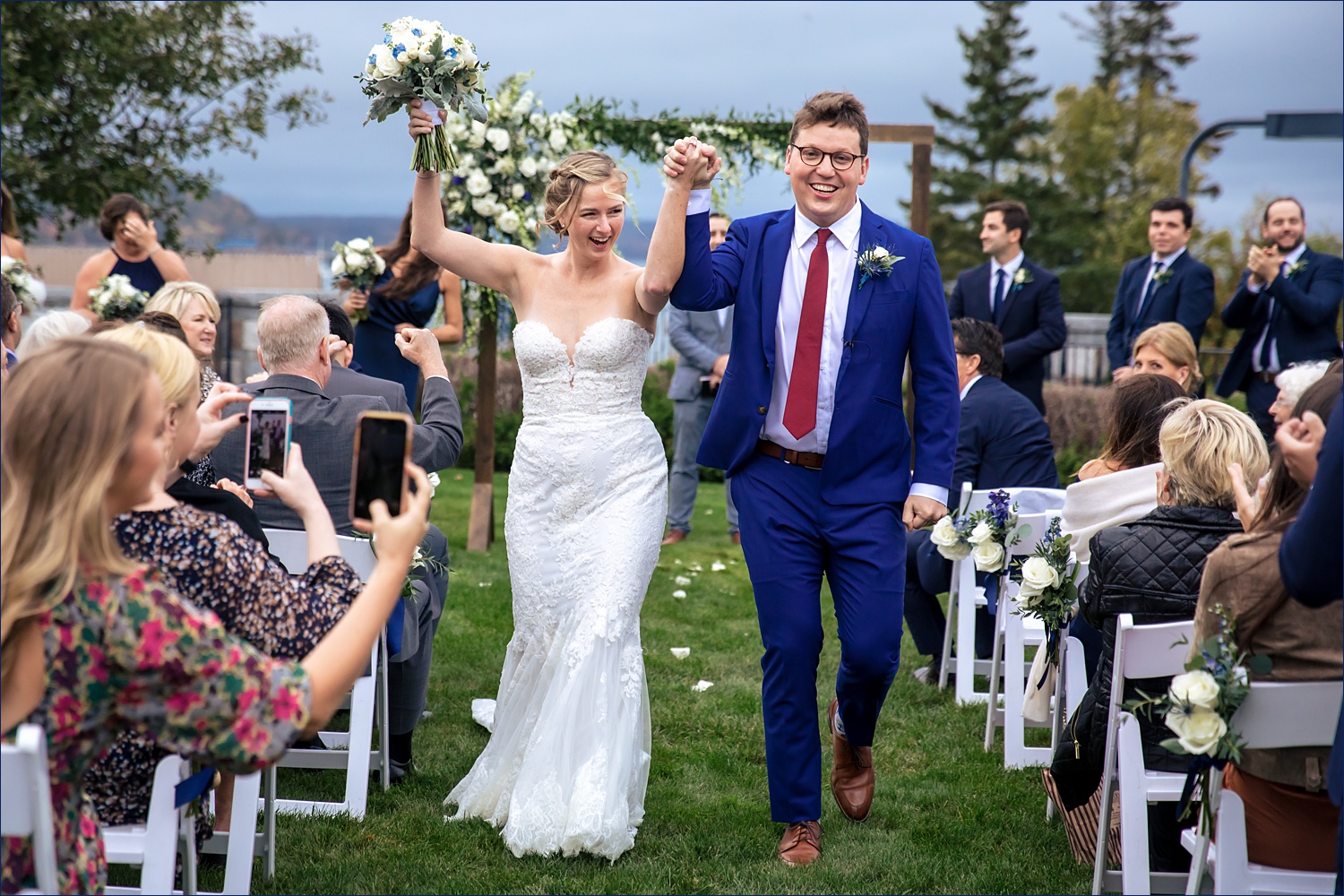 The married couple walks back up the aisle at their outdoor ceremony at Bar Harbor Club in Maine