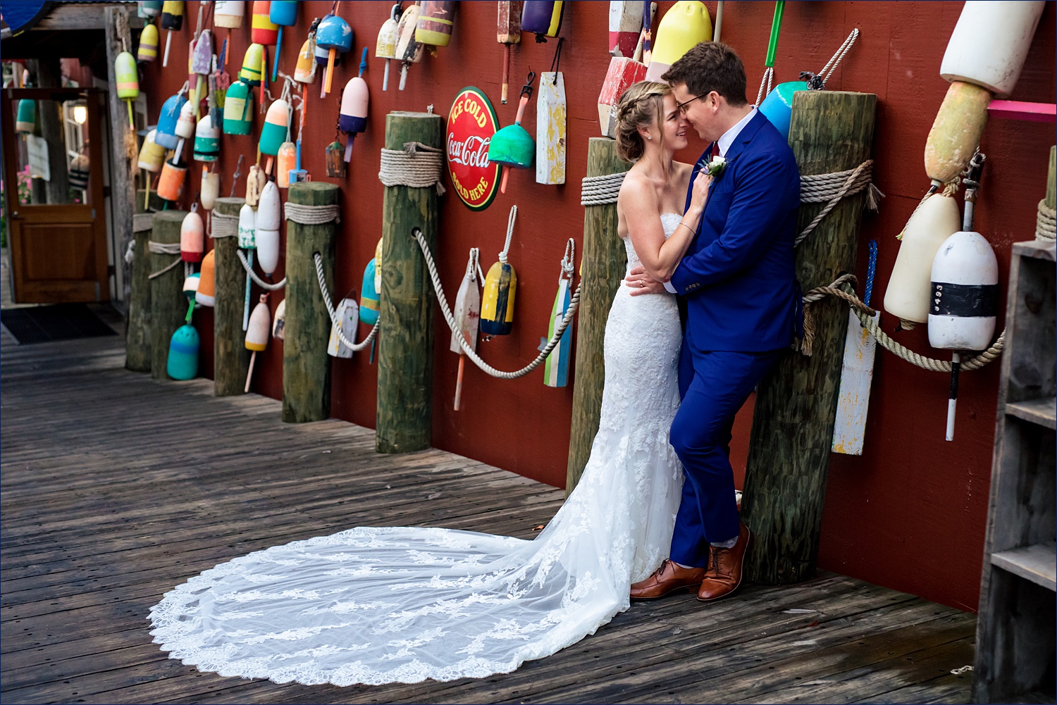 Married couple in front of a buoy wall in downtown Bar Harbor Maine after their wedding ceremony at Bar Harbor Club