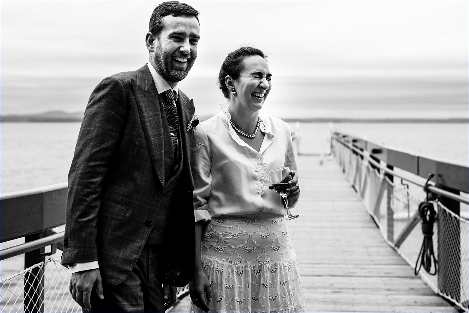 The bride and groom share a laugh together on their Maine wedding day on the dock at College of the Atlantic