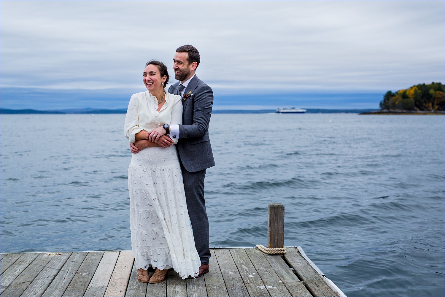 The groom holds onto the cold bride on on the waters of Bar Harbor Maine