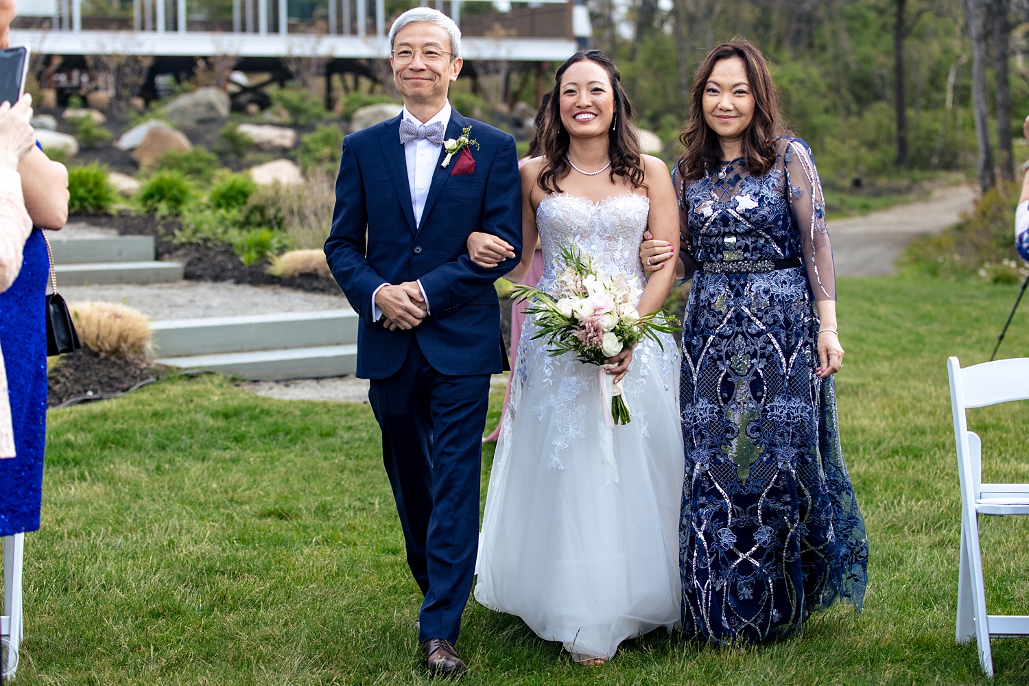 The bride and her parents enter the outdoor wedding ceremony
