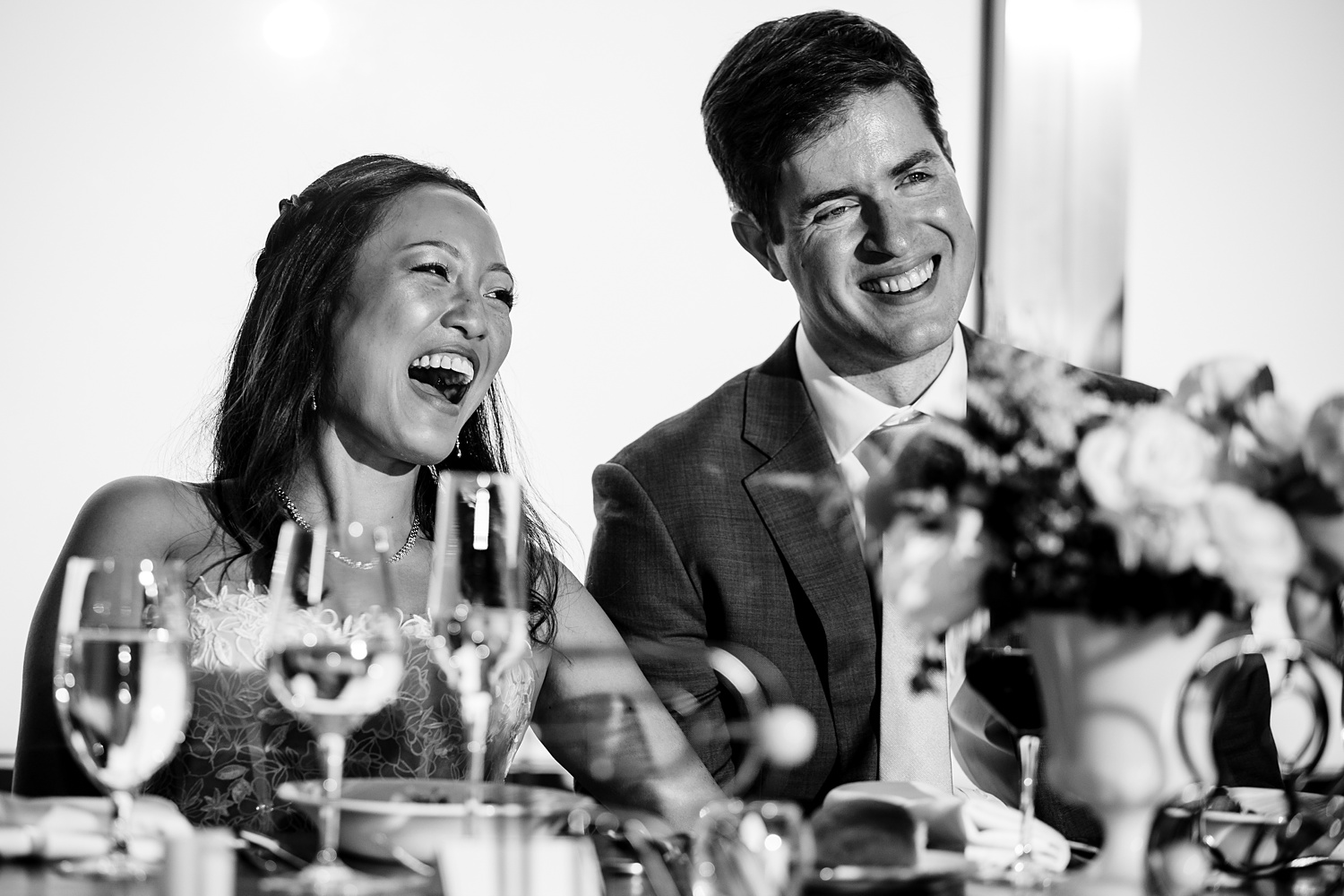 The couple laugh at a toast on their wedding day in Maine