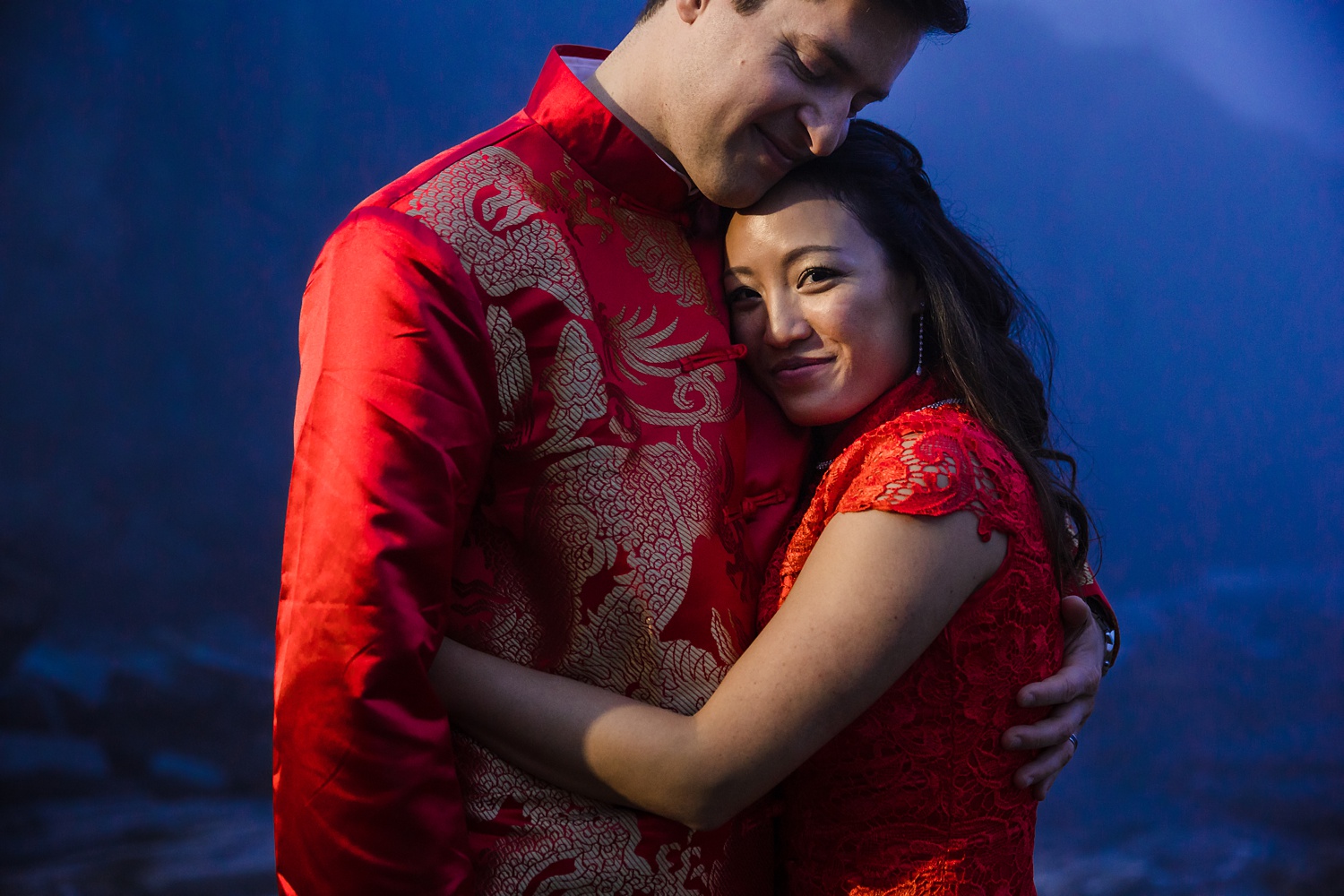 An embrace in the traditional Chinese wedding attire at Cliff House in Maine