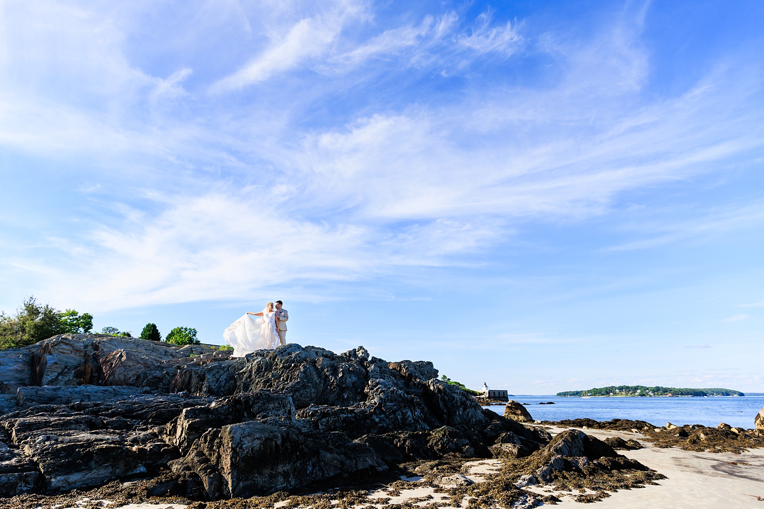 The bride and groom climb the rocks at Willard Beach in South Portland Maine