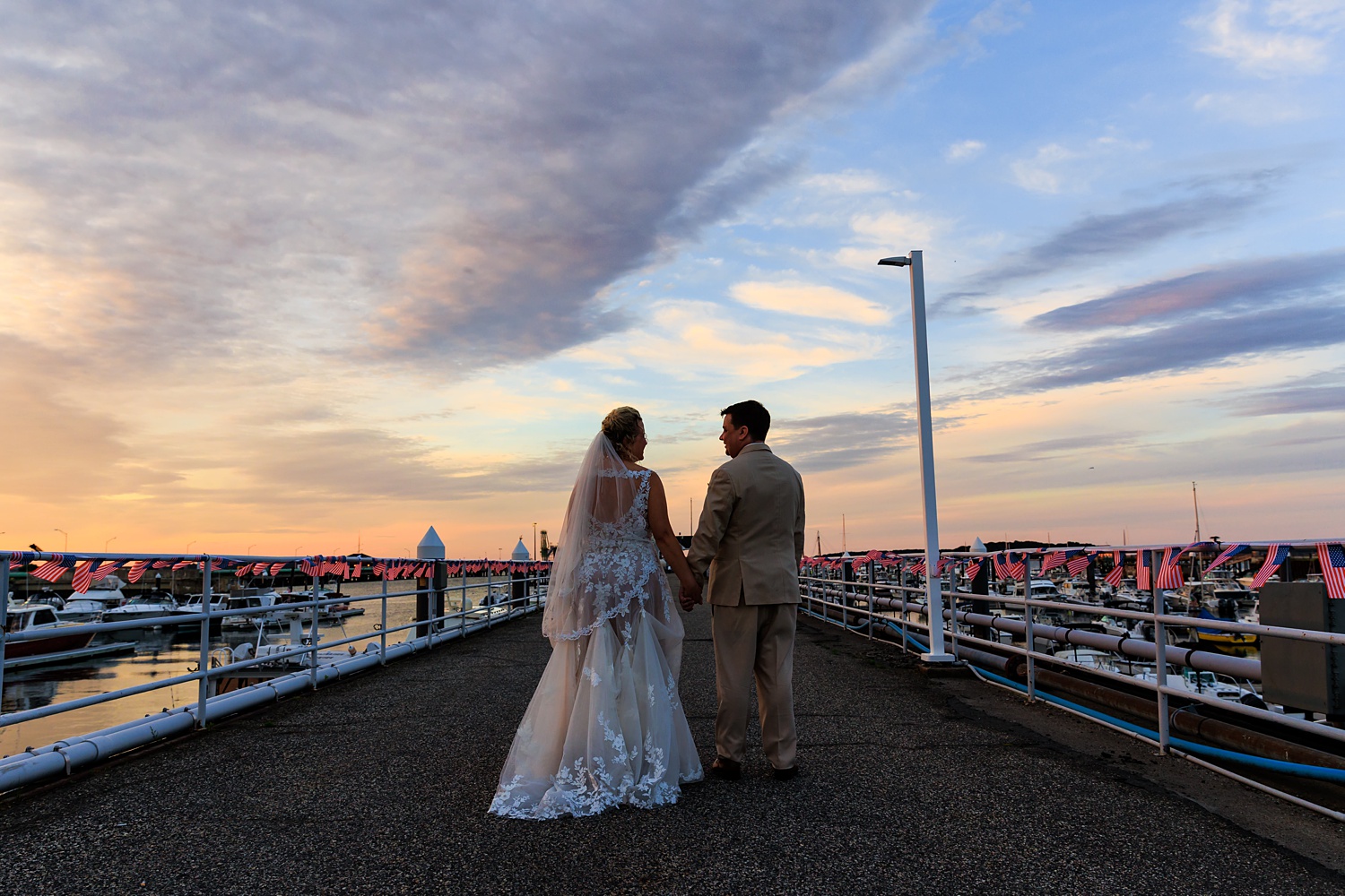 The bride and groom in front of the sunset on their wedding day in the marina