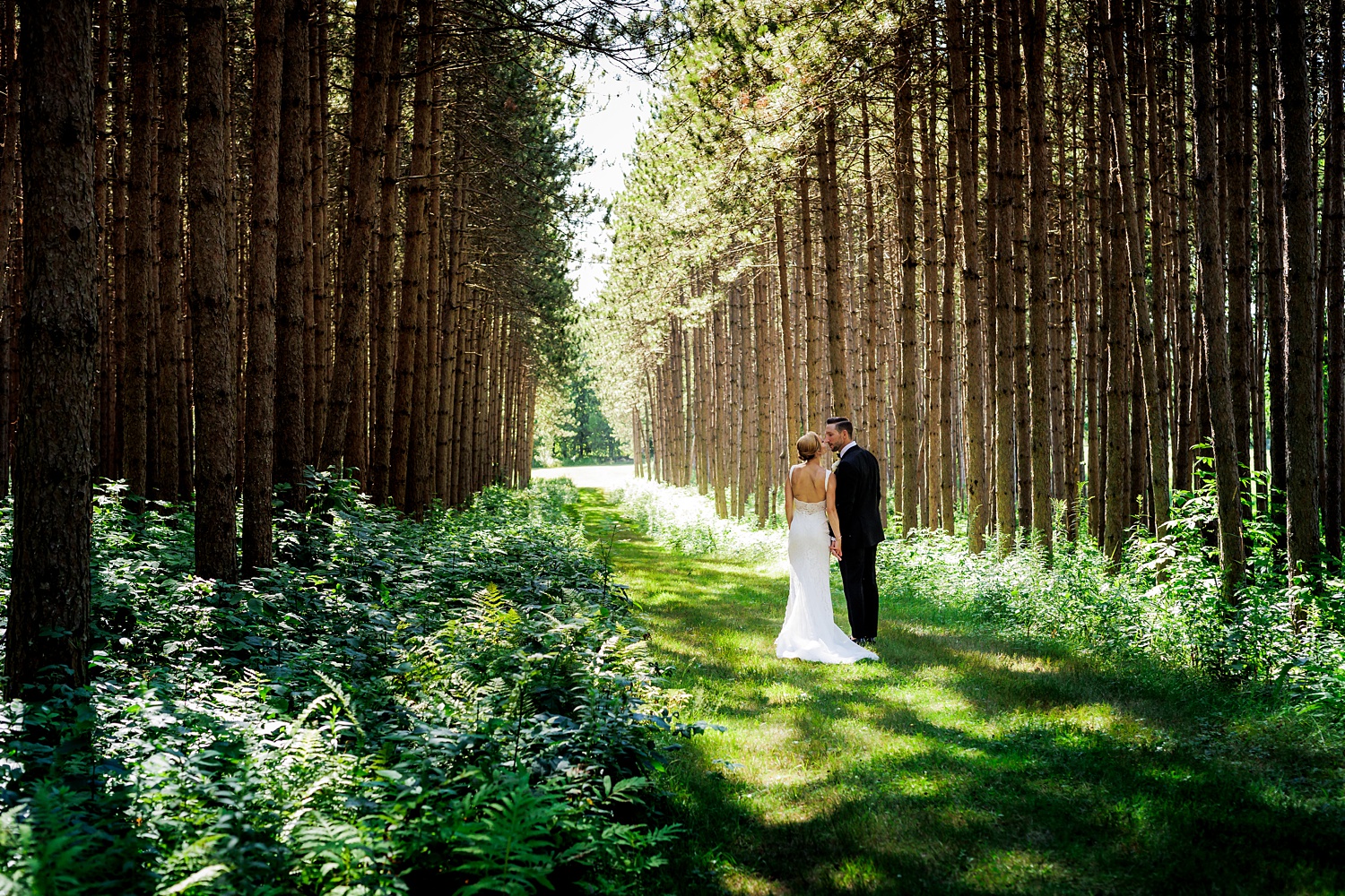 The newlyweds stand among the tall trees in the grove at Cunningham Farm in New Gloucester Maine