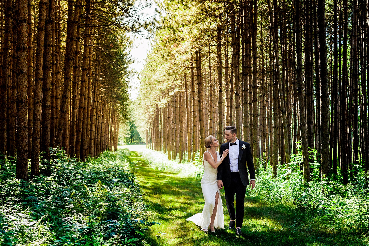 The newlyweds laugh as they walk among the tall trees in the grove at Cunningham Farm in New Glouchester Maine