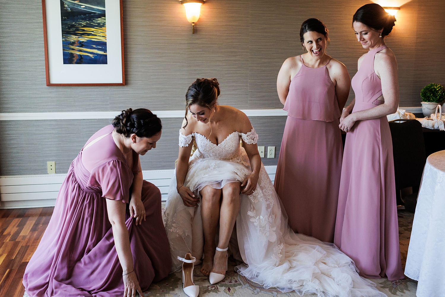 The bridesmaids help the bride into her wedding shoes